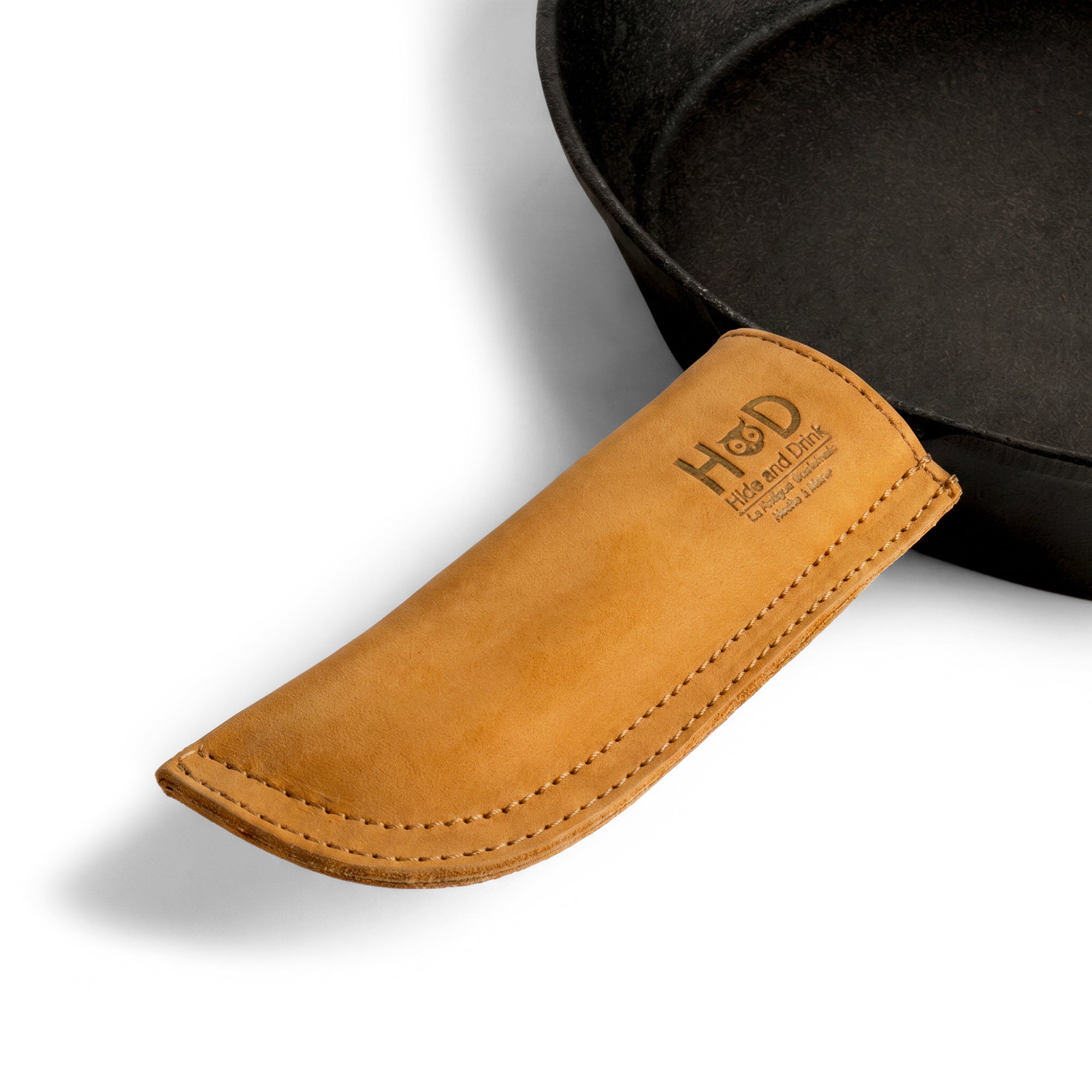 Hide & Drink Cast Iron Panhandle Cover presented in a stylish layout. This artisan hot handle protector offers both heat protection and comfortable grip, crafted from durable full grain leather with double stitching. Handcrafted in La Antigua Guatemala & Oaxaca Mexico, it's a must-have for any kitchen.