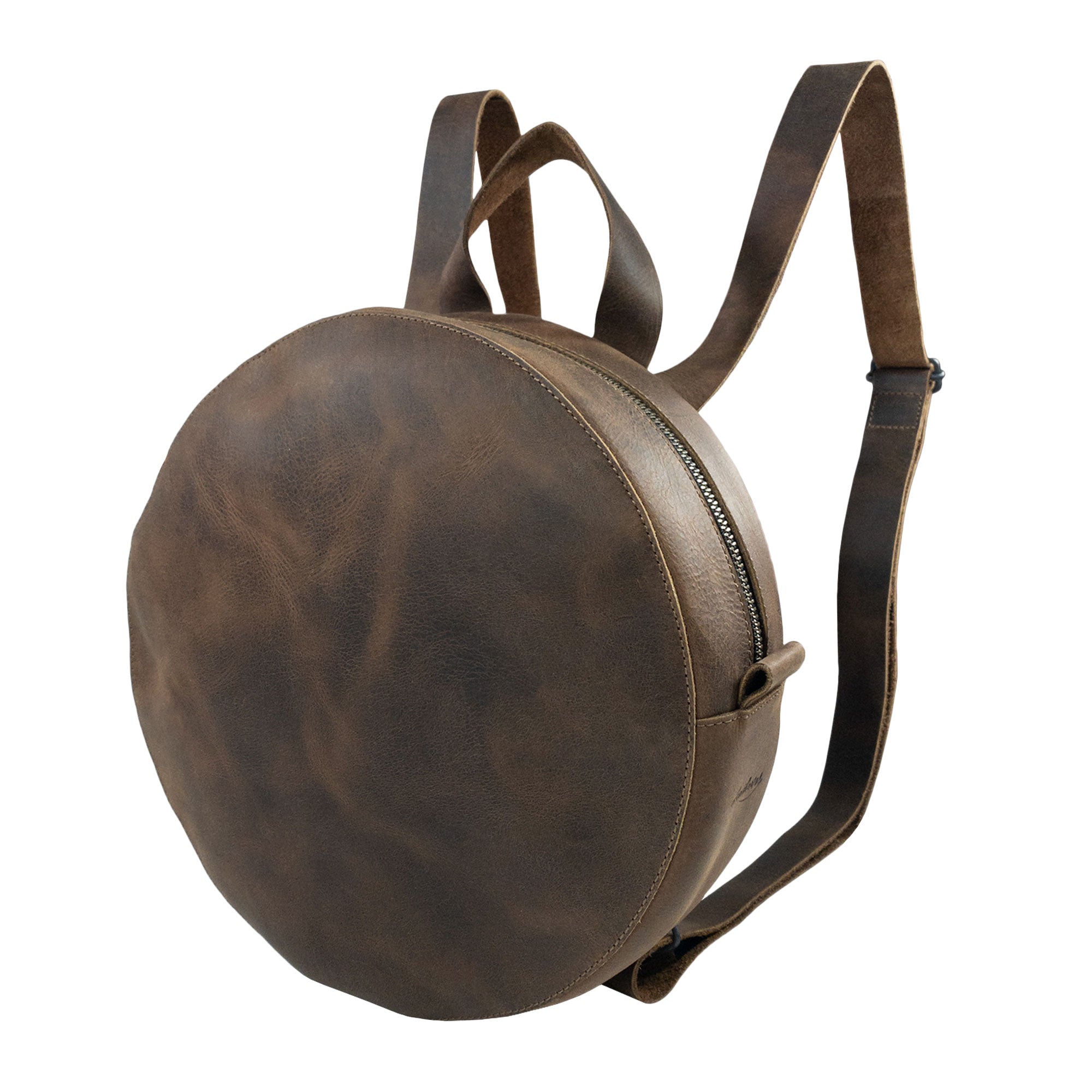 Heather's Circular Backpack featuring a round, full grain leather design, perfect as a travel accessory or casual daypack. This backpack includes adjustable straps and showcases the craftsmanship of small batch production, being hand cut and hand sewn by artisans in La Antigua Guatemala & Oaxaca Mexico.