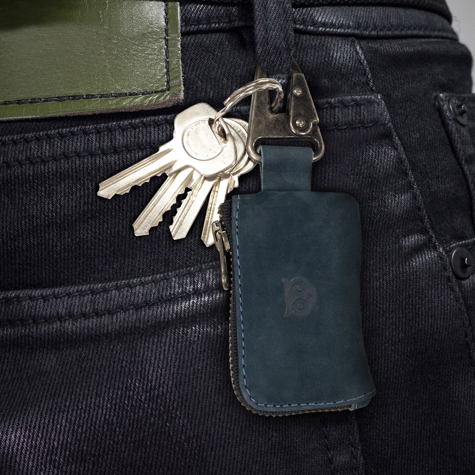 A Car Key Holder by Hide & Drink clipped onto a belt loop, designed for quick access to keys and cash. This artisan-made full grain leather accessory also holds headphone and charging cables, memory cards, and flash drives, handmade in La Antigua Guatemala & Oaxaca Mexico.