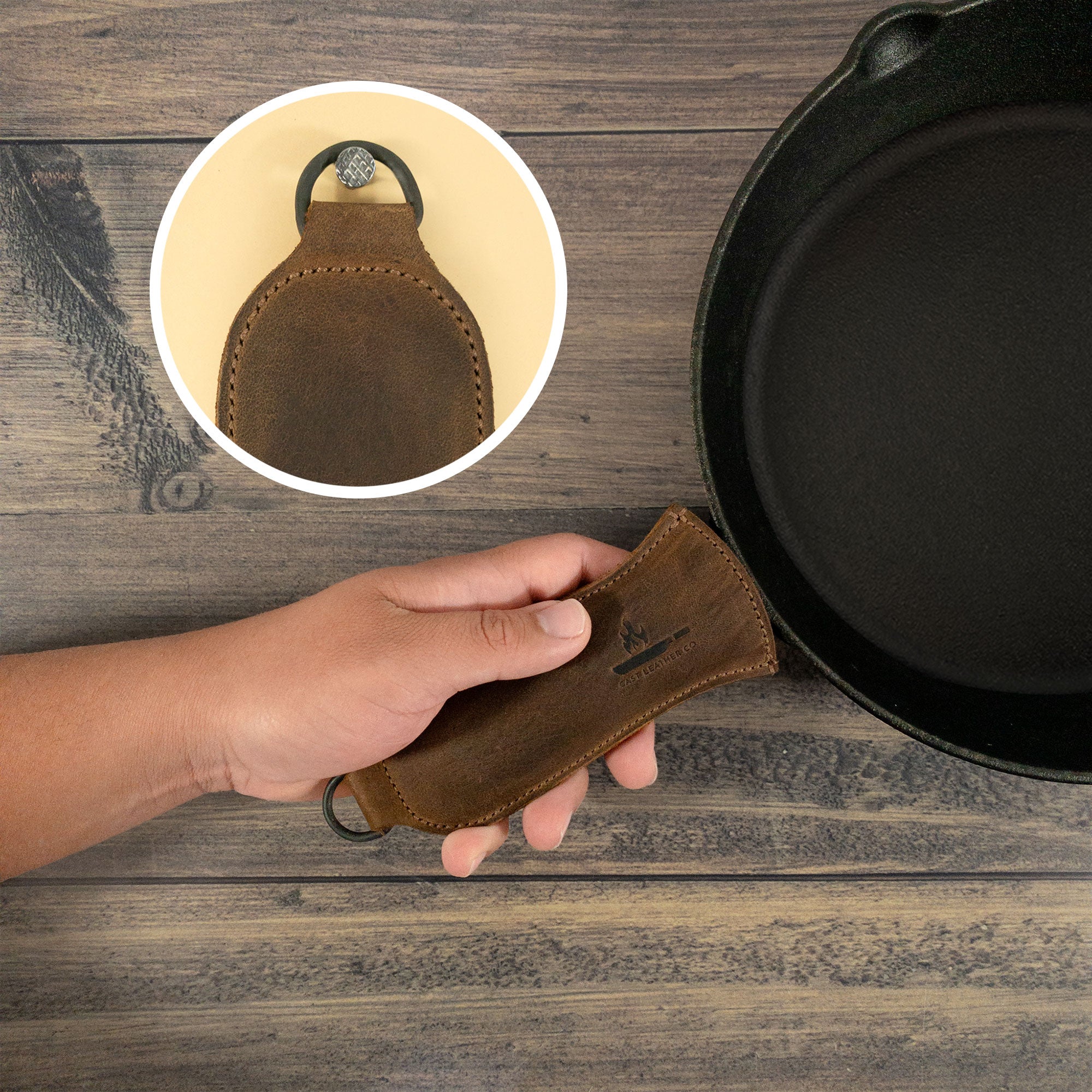 Hanging Pan Handle Cover by Cast Leather Co. being held, highlighting the ergonomic design of this Hot Handle Panhandle with Half Ring. Made from full grain leather, it ensures cookware slides on/off easily onto metal skillet grips. This artisan creation reflects hand cut, hand sewn craftsmanship in La Antigua Guatemala & Oaxaca Mexico.