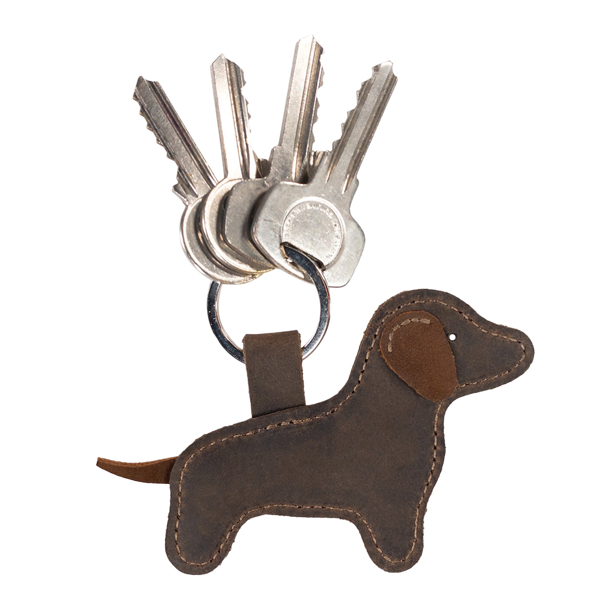 The Dog Keychain by Hide & Drink is a stylish accessory for your keys, illustrated here with keys attached. This dog-shaped keyring, crafted from durable Full Grain Leather, highlights the brand's commitment to handmade, artisan products, featuring a cute stuffed animal ornament design made with love in La Antigua Guatemala & Oaxaca Mexico.