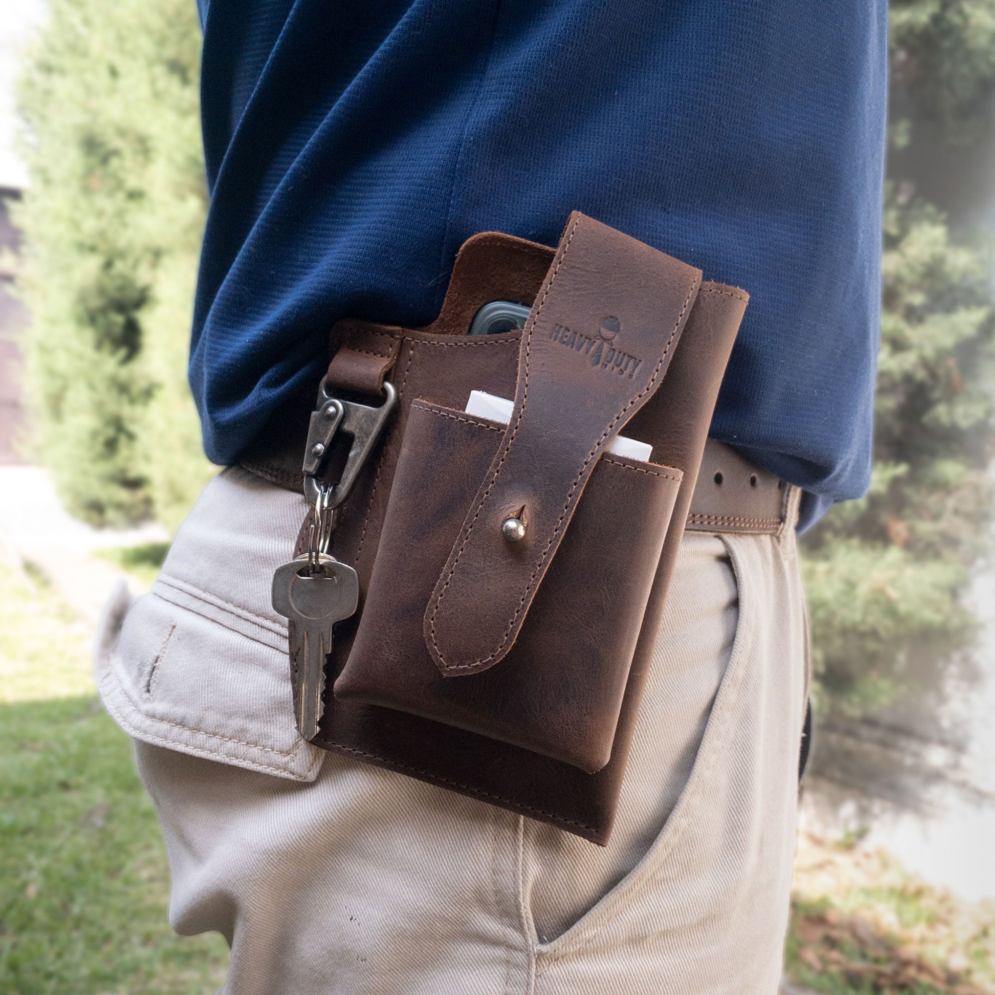 Heavy Duty Hide Rustic Phone & Cigarette Pack Holder worn on a belt, demonstrating its utility as a tactical organizer. This handmade accessory made from full grain leather is designed for outdoor protection, combining artisan skills from La Antigua Guatemala & Oaxaca Mexico with practical functionality.