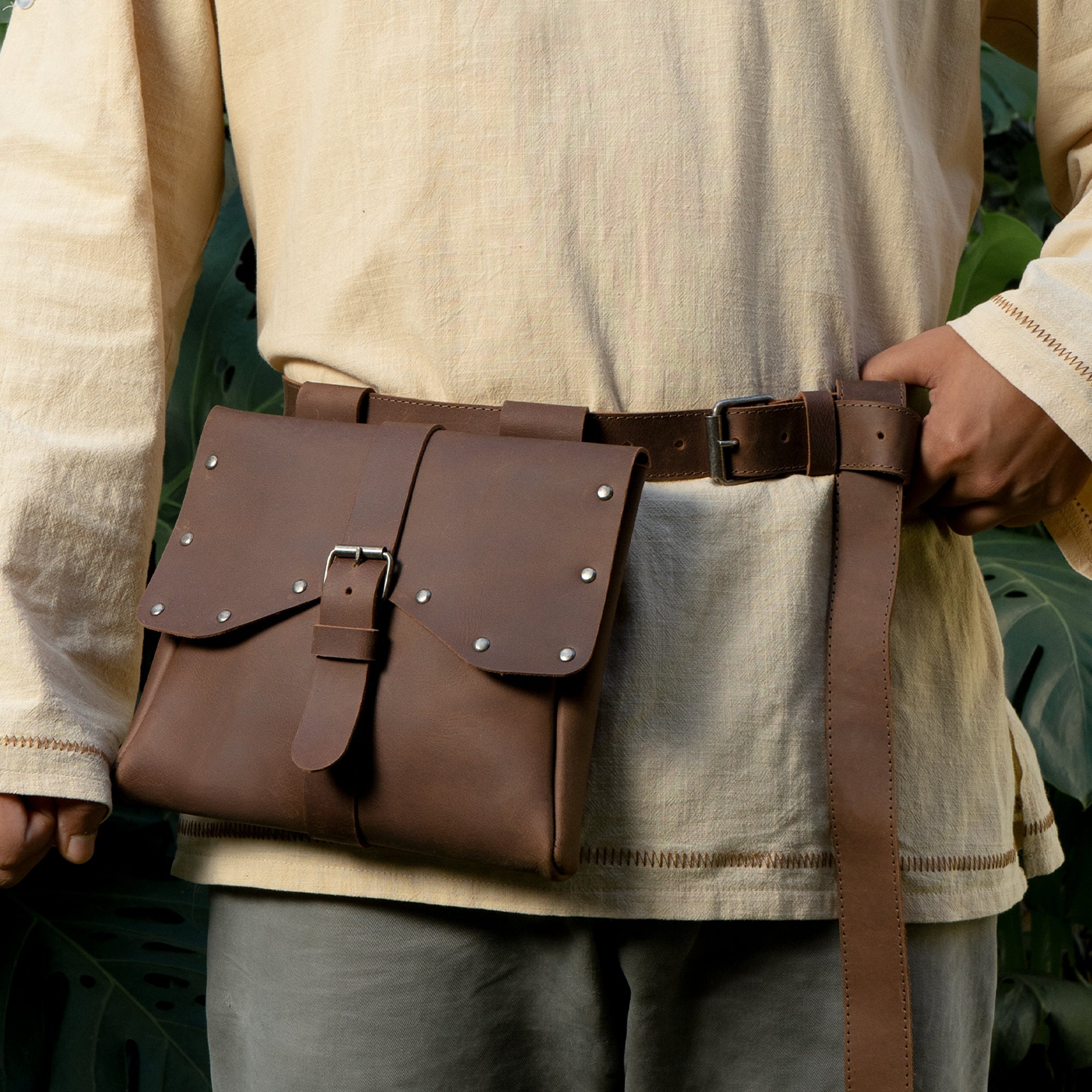 A person wearing the Viking Style Waist Bag with Belt by Hide & Play, featuring a secure buckle closure. This waist bag is ideal for cosplay and costumes, crafted from high-quality full grain leather, representing small batch production, hand cut and sewn by artisans in La Antigua Guatemala & Oaxaca Mexico.
