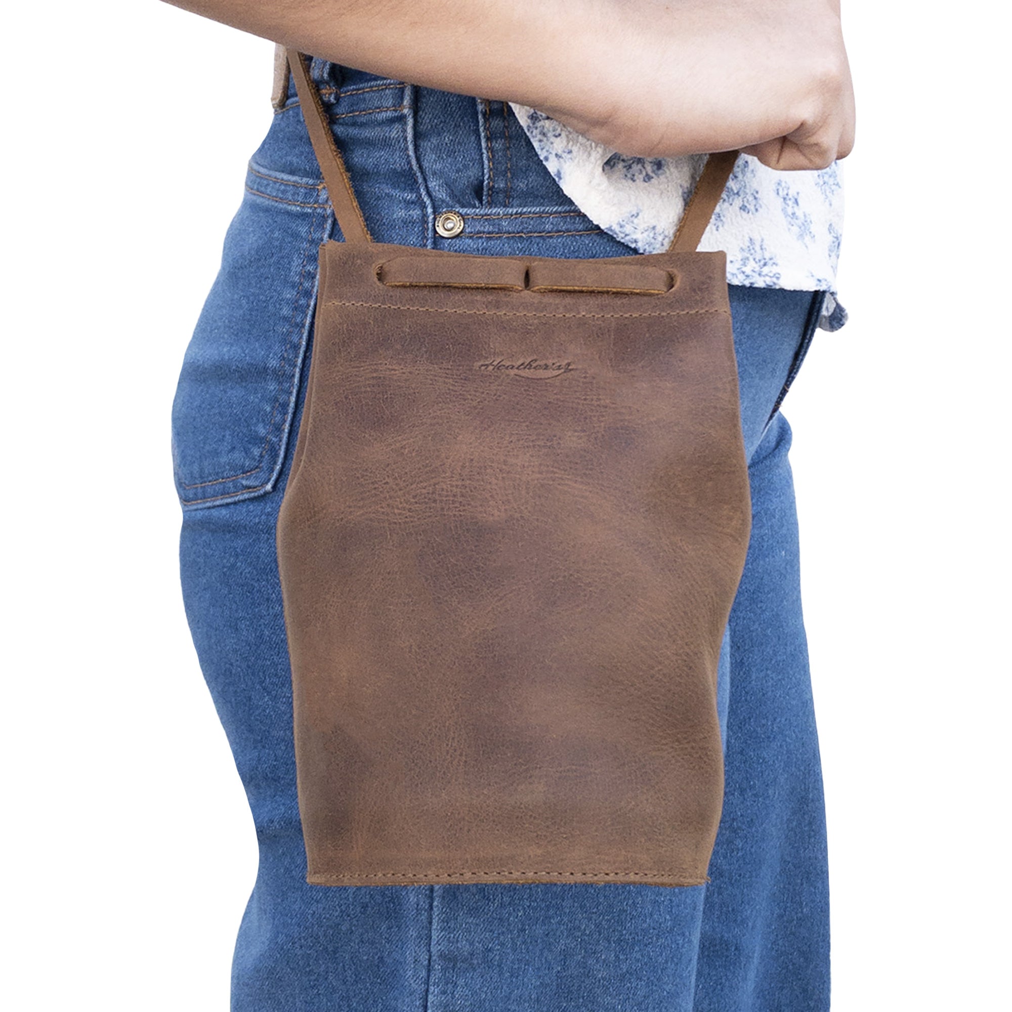 A person wearing Heather's Cylinder Shoulder Phone Bag, a trendy cylinder-shaped purse with an adjustable shoulder strap. Crafted from full grain leather, this crossbody bag showcases the artisan skills from StockyardX, featuring small batch production and hand cut, hand sewn details. Handmade in La Antigua Guatemala & Oaxaca Mexico.