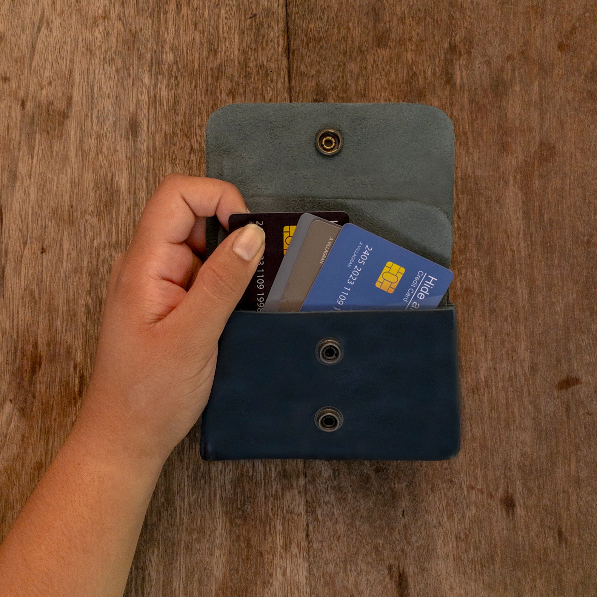 A hand using the gray Double Pouch Card Wallet by Hide & Drink to retrieve cards. This Leather Double Pouch Card Wallet is practical as a card organizer, cash holder, and coin pouch, designed for men and women, made from Full Grain Leather in La Antigua Guatemala & Oaxaca Mexico.