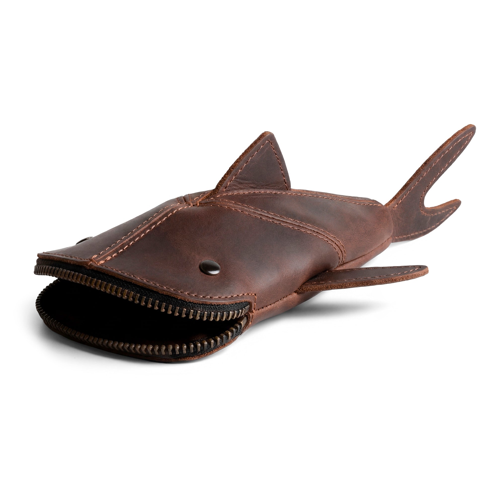 This Leather Shark Pouch by Hide & Drink showcases a unique shark design with an open zipper, ideal for storing scissors, cables, and other essentials, made from high-quality full grain leather through artisan techniques in small batch production, and features hand-cut and hand-sewn craftsmanship.
