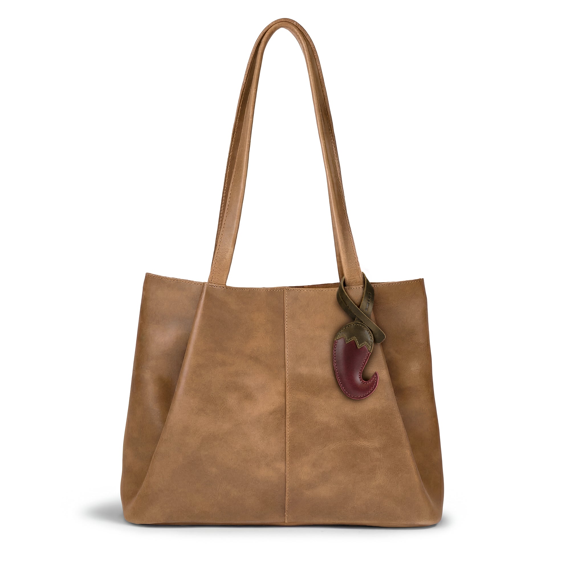 A stylish tan tote adorned with the Hot Pepper Bag Charm by Hide & Drink, illustrating how this full grain leather accessory complements handbags and backpacks. Handmade in La Antigua Guatemala & Oaxaca Mexico, this artisan charm emphasizes individuality and is crafted through hand cut and hand sewn methods. It's the perfect ornament for women wanting a unique touch in their purse charm collection.