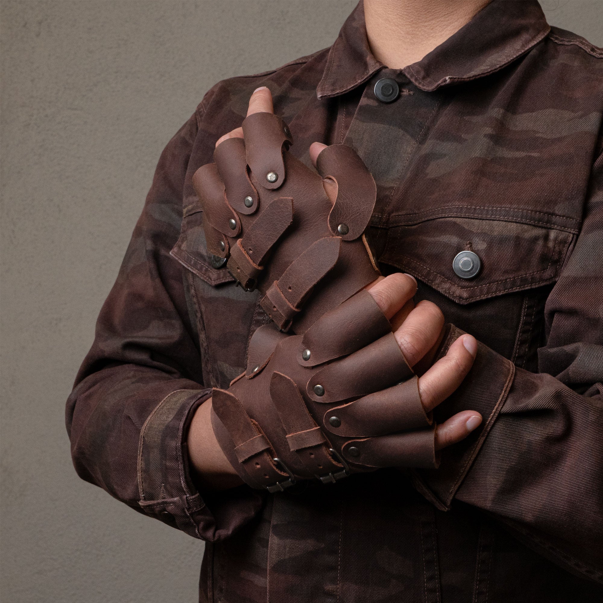 A model showcasing the Set of 2 Steampunk Gloves in action, highlighting the unique design and fit. Ideal for cosplay and themed parties, these gloves are made from full grain leather by Hide & Play, emphasizing their handcrafted artisan quality from La Antigua Guatemala, perfect vintage gloves for any costume.
