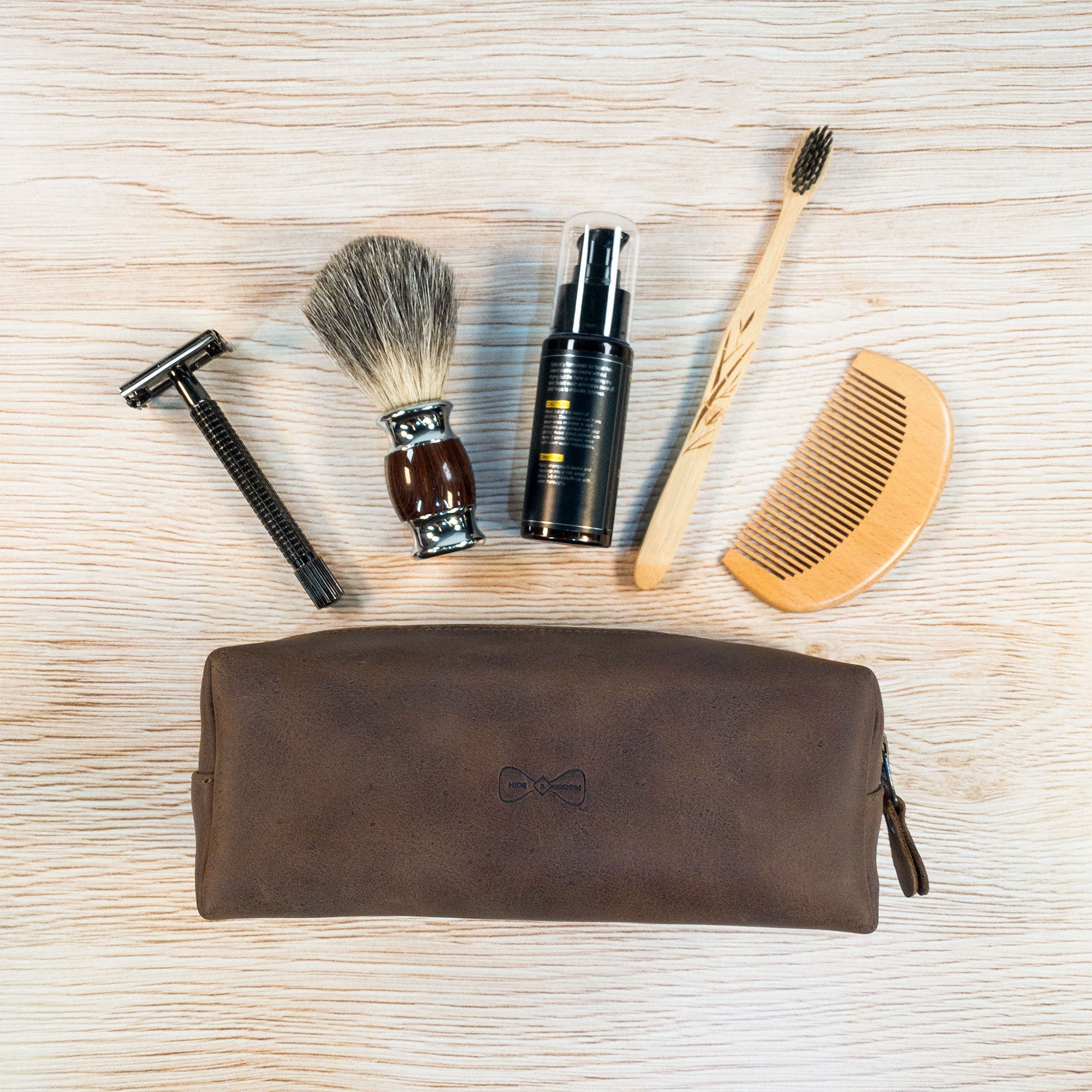 Rectangular Toiletry Bag for Groomsmen by Hide & Groom, displayed with grooming essentials like a razor and comb. This bathroom bag is great for best men and bachelors for travel and wedding ceremonies, made from durable full grain leather in La Antigua, Guatemala.