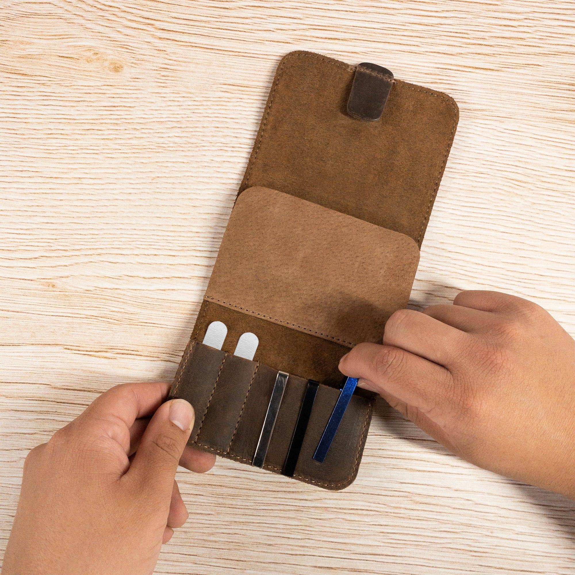 Person's hands holding the Rustic Case for Groomsmen Accessories by Hide & Groom, showcasing the organized compartments designed for travel essentials. This full grain leather bag is perfect for cufflinks and collar stays, highlighting artisan craftsmanship from La Antigua Guatemala.