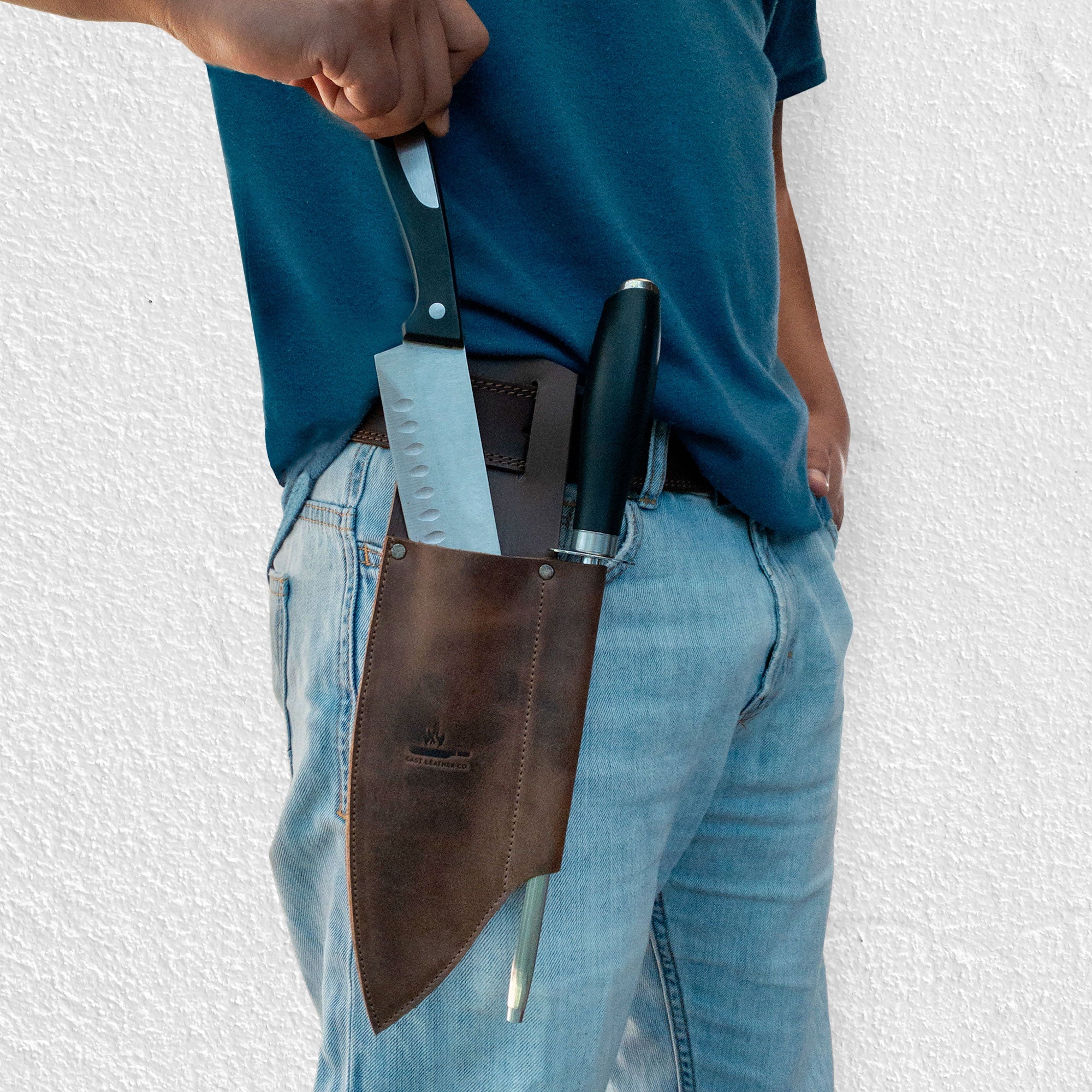 Knife Sheath with Sharpener Slot by Cast Leather Co., worn on a belt showcasing a rustic sleeve for a chef knife and sharpener. This knife holster for belt is made from high-quality full grain leather, emphasizing small batch production and artisan skills, handcrafted in La Antigua Guatemala.