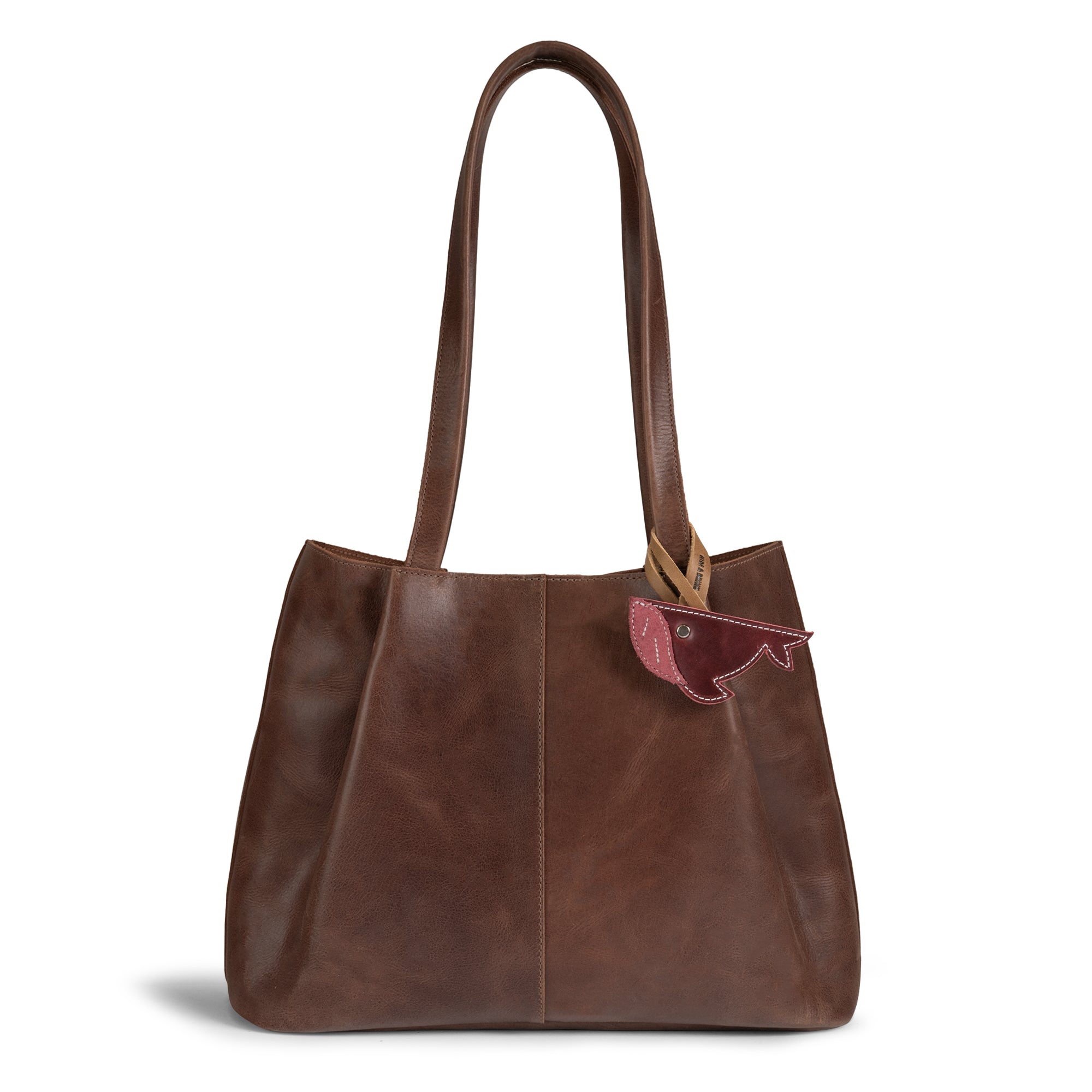 Stylish Whale Bag Charm by Hide & Drink featured on a chic brown leather tote bag. This Whale Bag Charm for Handbags enhances the look of any accessory as a perfect Purse Charm for Tote & Backpacks. Made from high-quality full grain leather, this ornament for women represents artisan craftsmanship and is hand cut and hand sewn. Handmade in La Antigua Guatemala & Oaxaca Mexico.