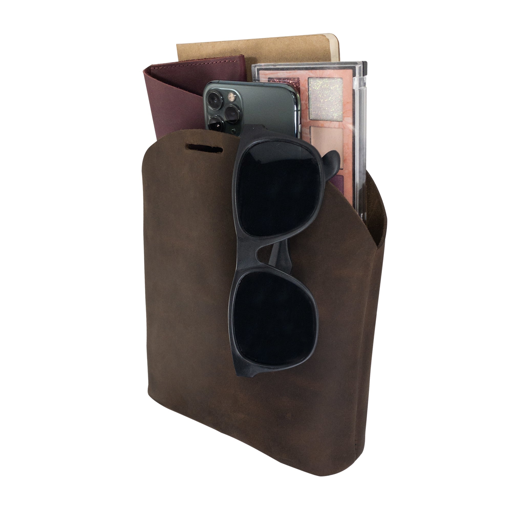 The interior of the Rounded Handbag by Hide & Drink, filled with essentials like a phone and notebooks, demonstrating its functionality as a travel organizer. Made of full grain leather, this handmade bag features exquisite craftsmanship with a focus on small batch production and fire branded elements, handmade in La Antigua Guatemala & Oaxaca Mexico.