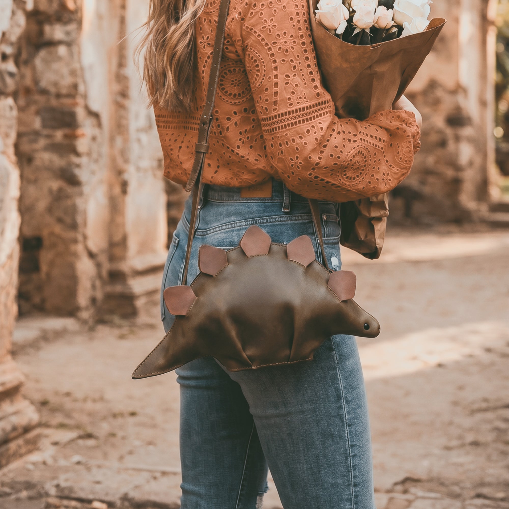 Dinosaur-Shaped (Stegosaurus) Shoulder Bag by Tudi Frudi modeled by a person, emphasizing its comfortable wear as a Crossbody Bag. Made from high-quality Full Grain Leather, this unique Messenger Bag is Handmade in La Antigua Guatemala & Oaxaca Mexico, showcasing true Artisan craftsmanship.