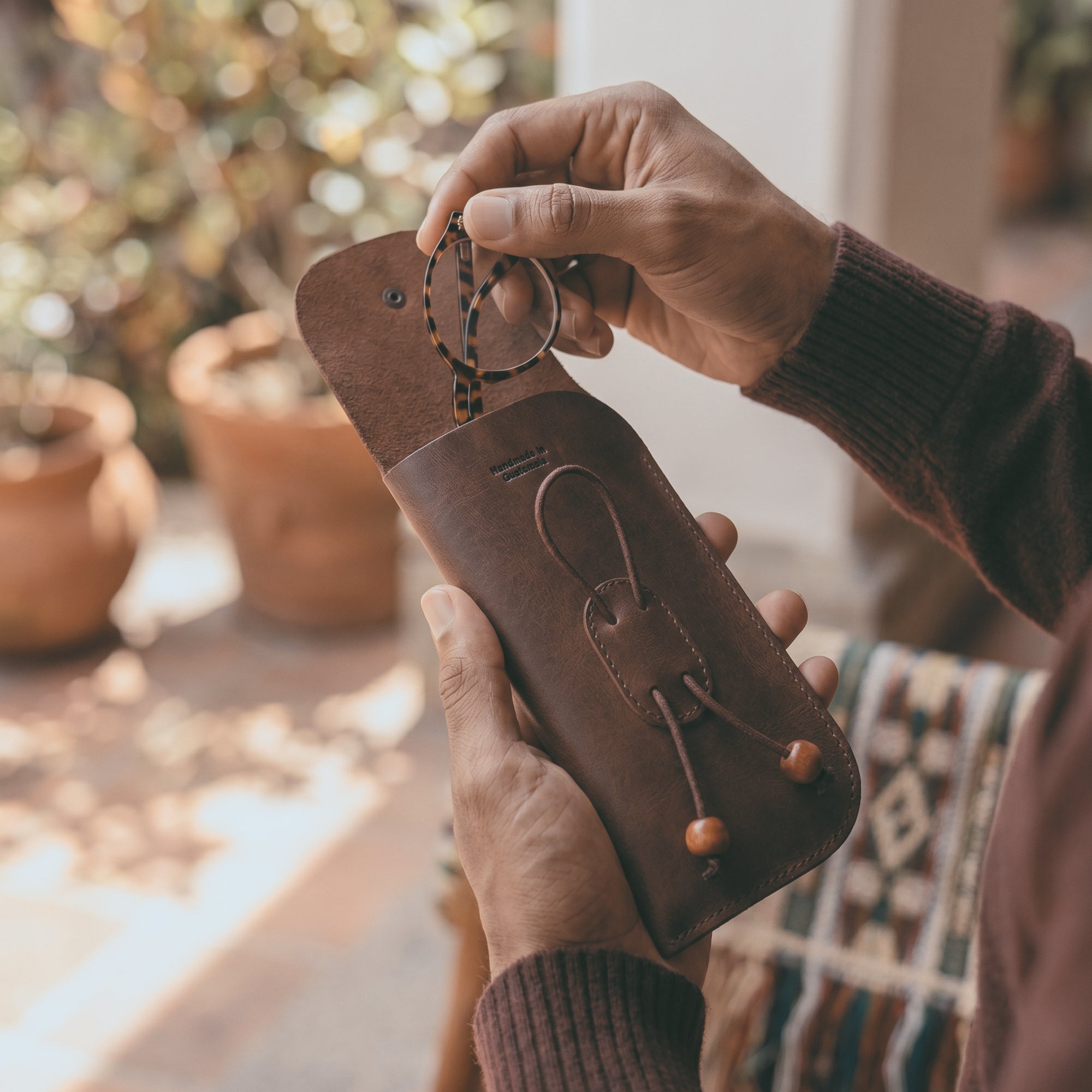 A person holding the Slim Eyeglasses Case by Hide & Drink, showcasing its functionality and craftsmanship. This leather glasses pouch is designed for sunglasses and eyeglasses, made from premium full grain leather. It’s an essential glasses pouch for travel, emphasizing small batch production and artisan detailing, handmade in La Antigua Guatemala & Oaxaca Mexico.