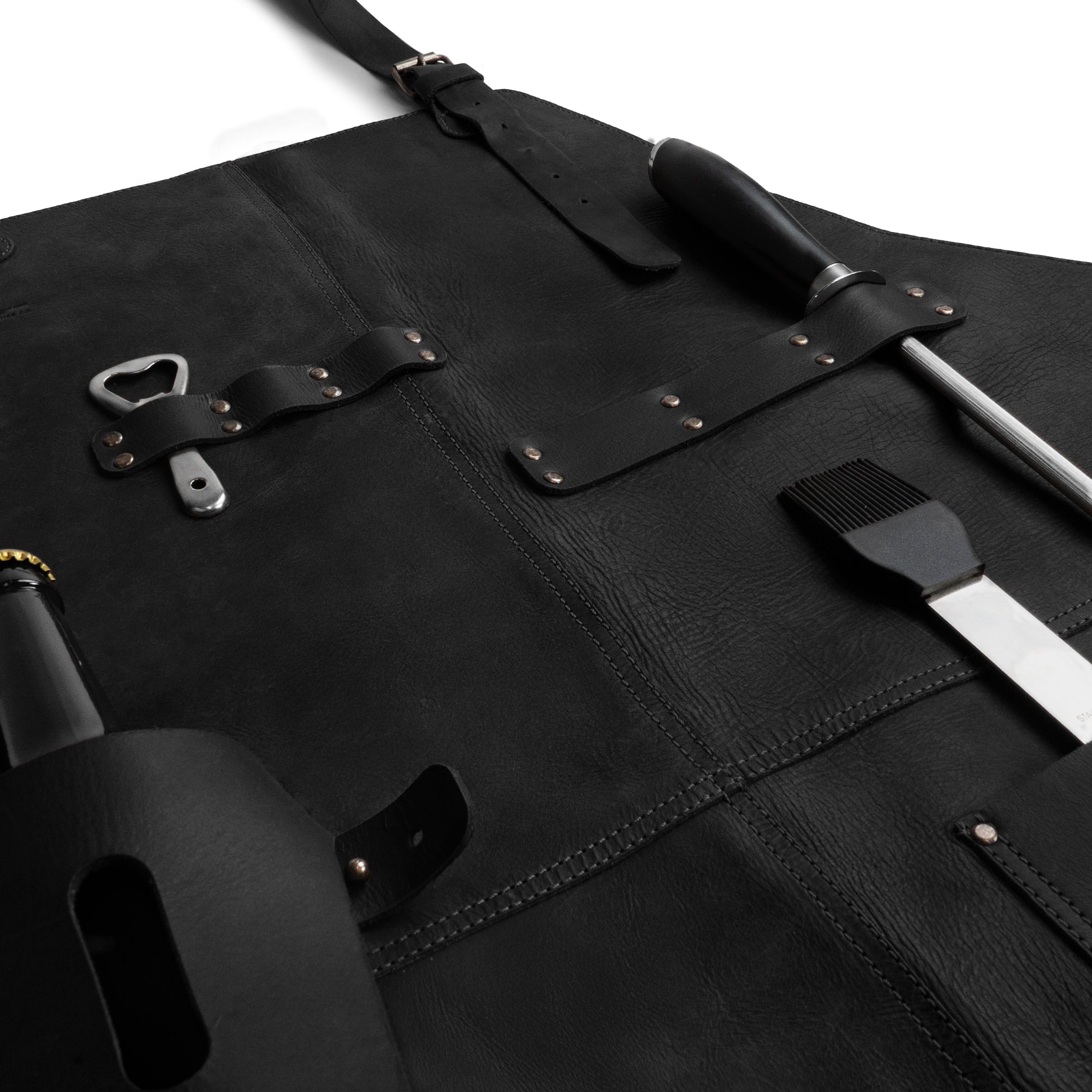 Measurement view of Cast Leather Co. BBQ Apron in black, presenting dimensions while highlighting its rustic chef design with adjustable neck strap. This artisan piece is made from full grain leather, ensuring quality and style for any cooking enthusiast.