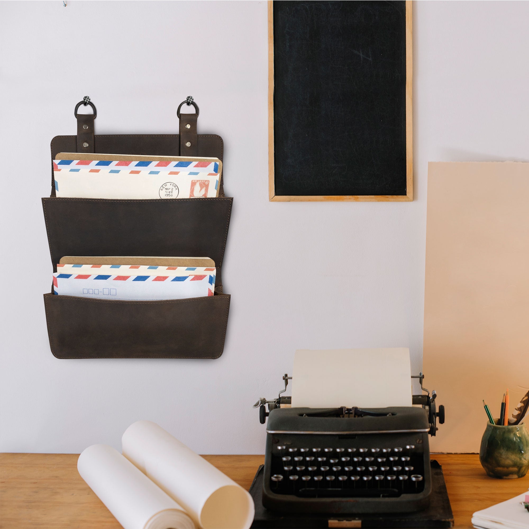 Hide & Drink Double Document Holder for Hanging mounted on a wall, adorned with letters, demonstrating its role as stylish wall mount file storage. Constructed with quality full grain leather, this item is a testament to artisan craftsmanship, small batch production, hand cut, hand sewn, and fire branded, handmade in La Antigua Guatemala & Oaxaca Mexico.