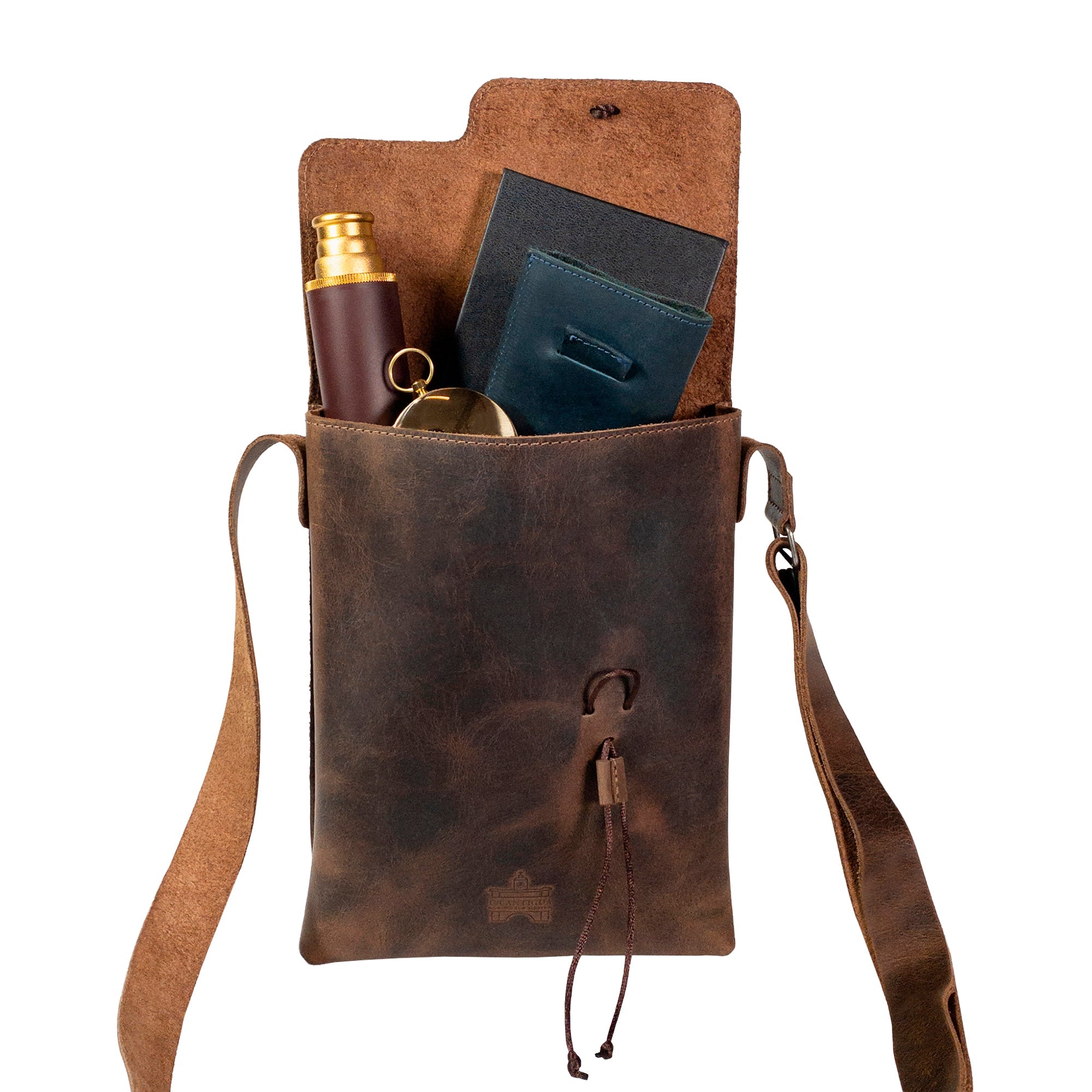 The interior of the La Antigua Treasure Crossbody Bag filled with essentials, highlighting its spacious design and rustic full grain leather material. A stunning vintage satchel ideal for everyday adventures, handcrafted in La Antigua Guatemala.