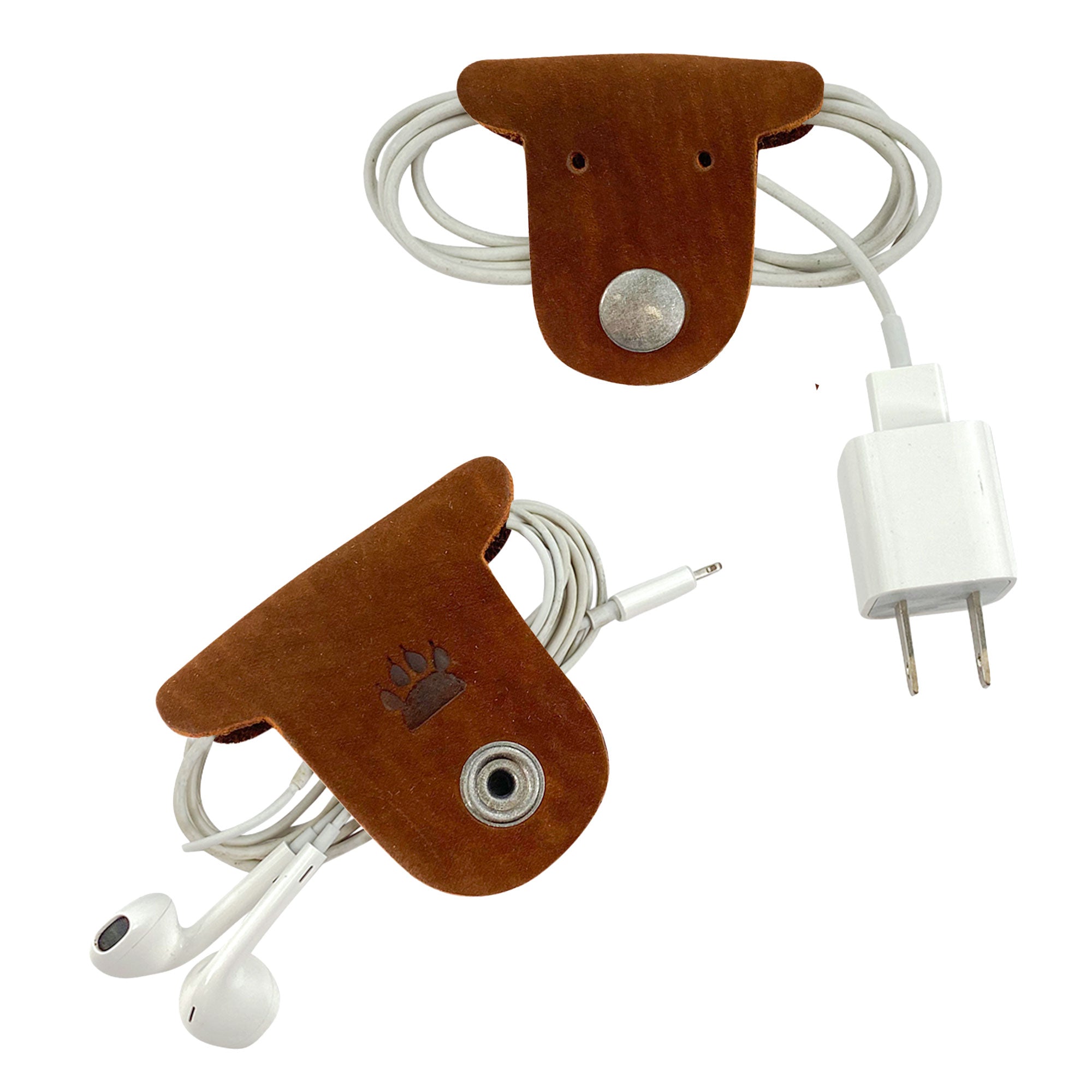 Two brown Dog Cord Keepers by Taco Dog, ideal for keeping your cables neat and organized. These artisan-crafted accessories, made from full grain leather, feature clip snaps for easy travel management. Discover the unique charm of handmade goods from La Antigua Guatemala.