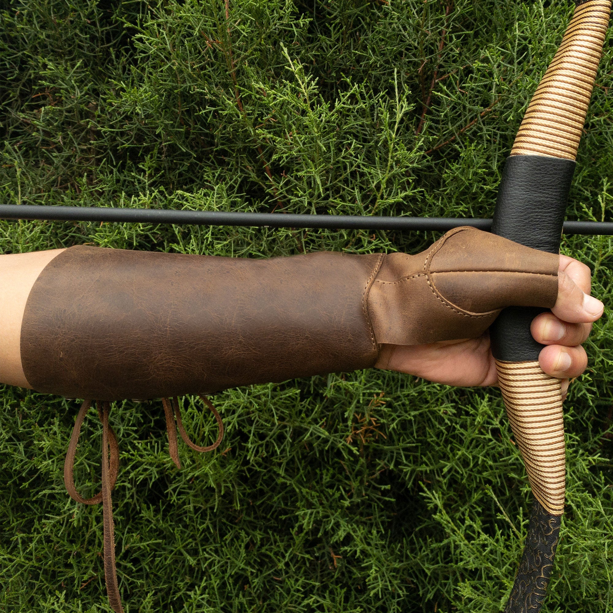The Archery Forearm Protector by Valhalla Gear being worn while holding a bow, demonstrating its functionality for bow shooting practice. Made from high-quality full grain leather, this arm guard is perfect for training and cosplay, reflecting the commitment to artisan craftsmanship in La Antigua Guatemala & Oaxaca Mexico.