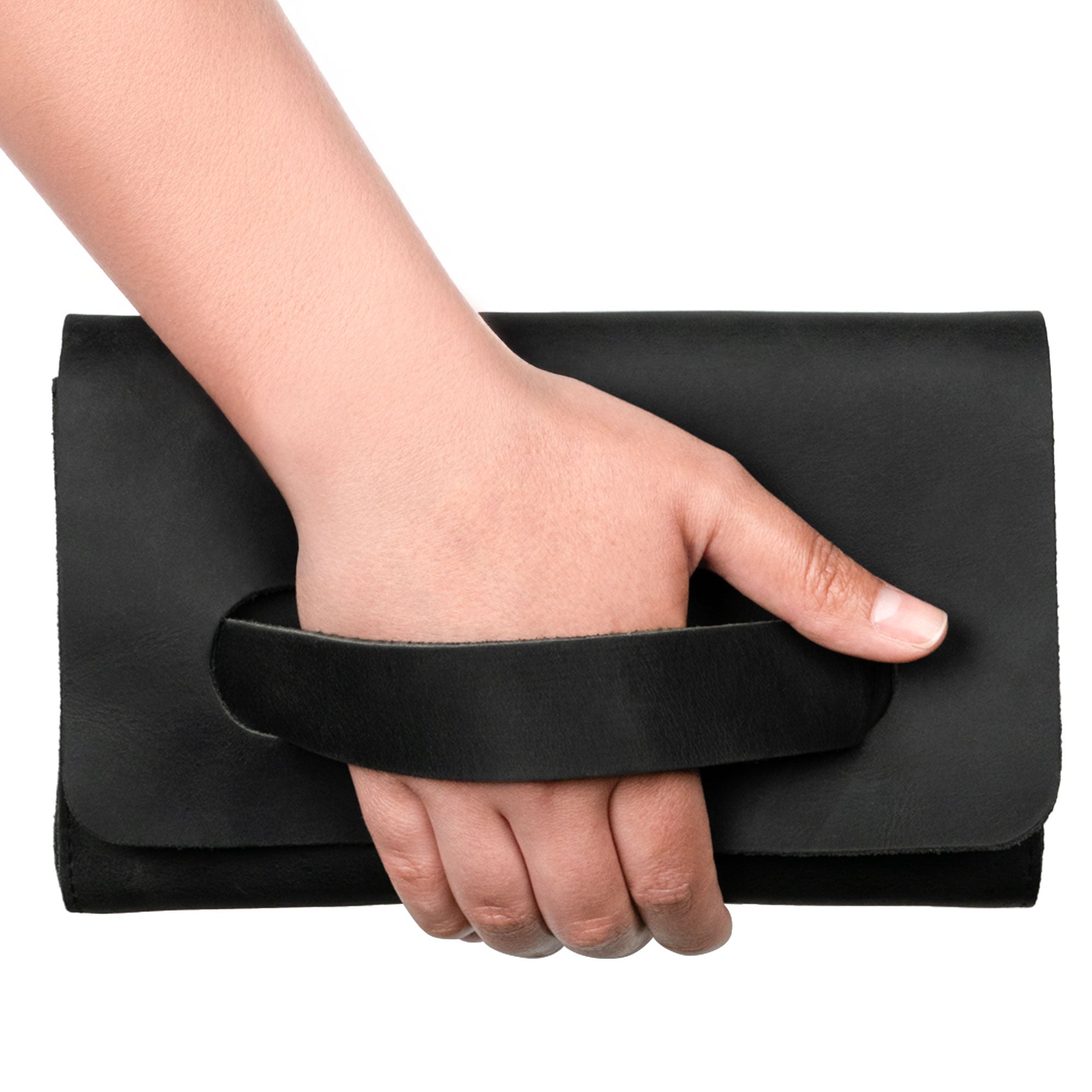 A hand holding the black Clutch Bag With Handle from Hide & Drink. This Full Grain Leather Clutch Bag is perfect for women seeking a fashionable handbag or night bag, showcasing handmade quality from artisans in La Antigua Guatemala & Oaxaca Mexico.