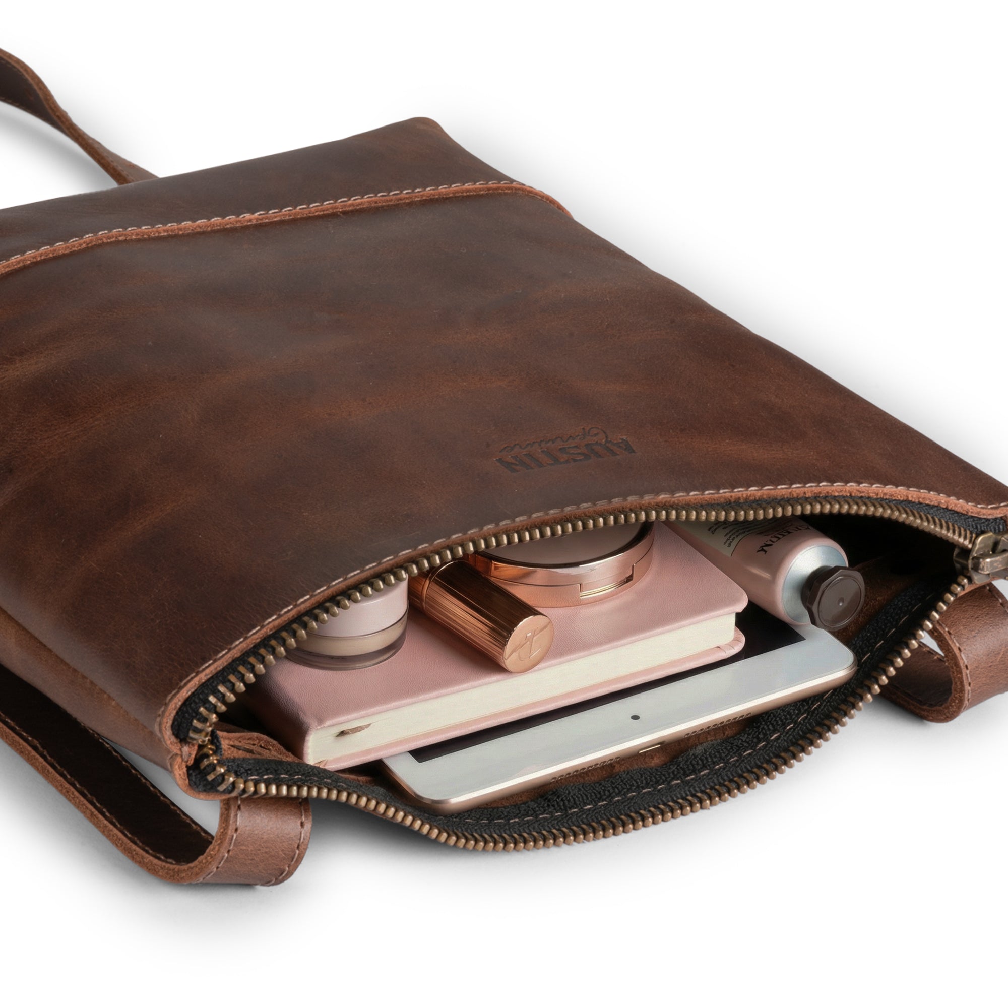 The Zilker Crossbody Bag by Austin Genuine, unzipped to reveal its spacious interior, crafted from full grain leather and designed with the vibrant culture of Austin in mind, showcasing artisan craftsmanship and small batch production.
