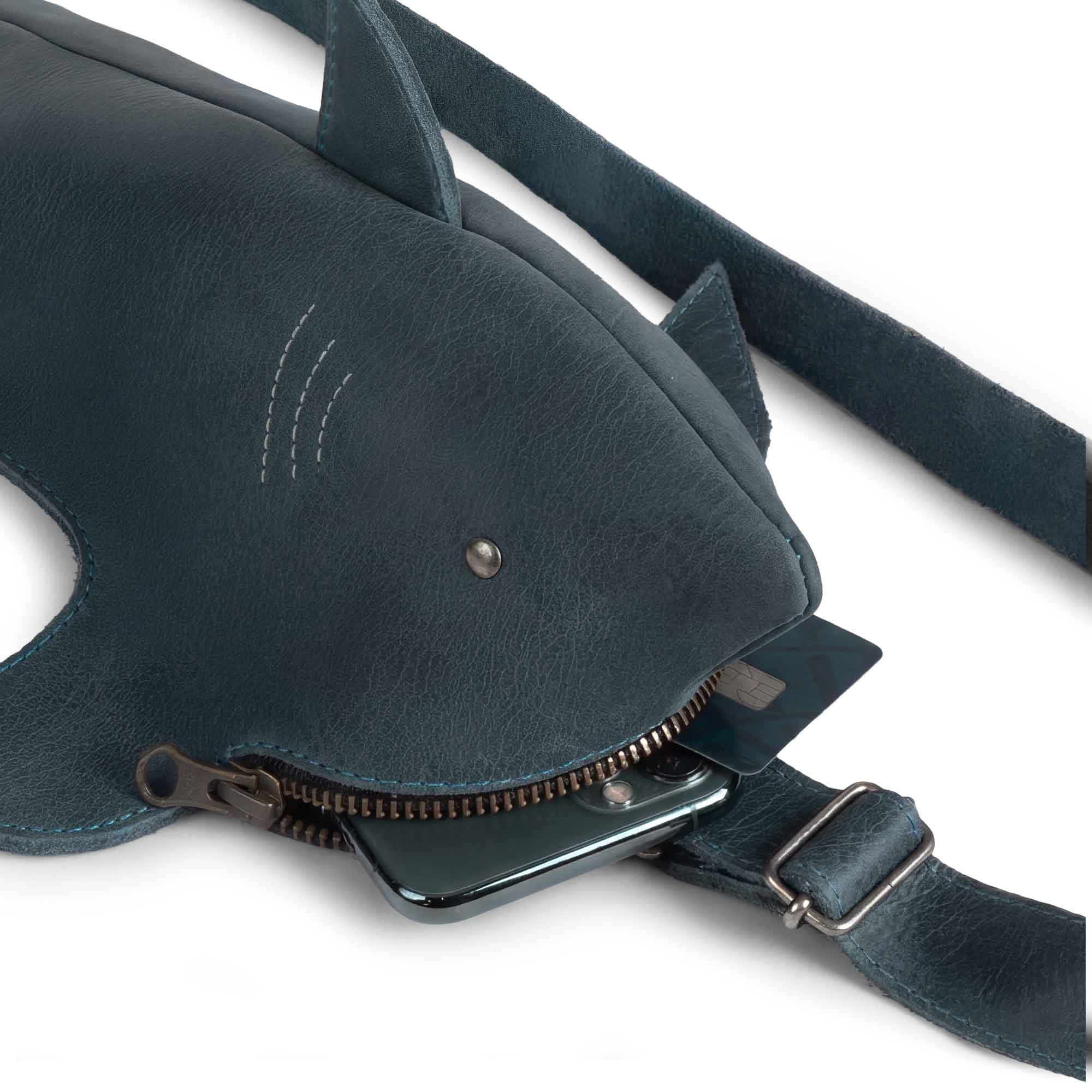 Close-up of the Shark-Shaped Crossbody by Tudi Frudi, featuring a durable Leather Shark-Shaped Sling Bag with Adjustable Strap. This functional Crossbody Purse serves as a Messenger Bag, perfect for carrying essentials. Crafted from Full Grain Leather, it's handmade in La Antigua Guatemala, ensuring high quality and unique style.