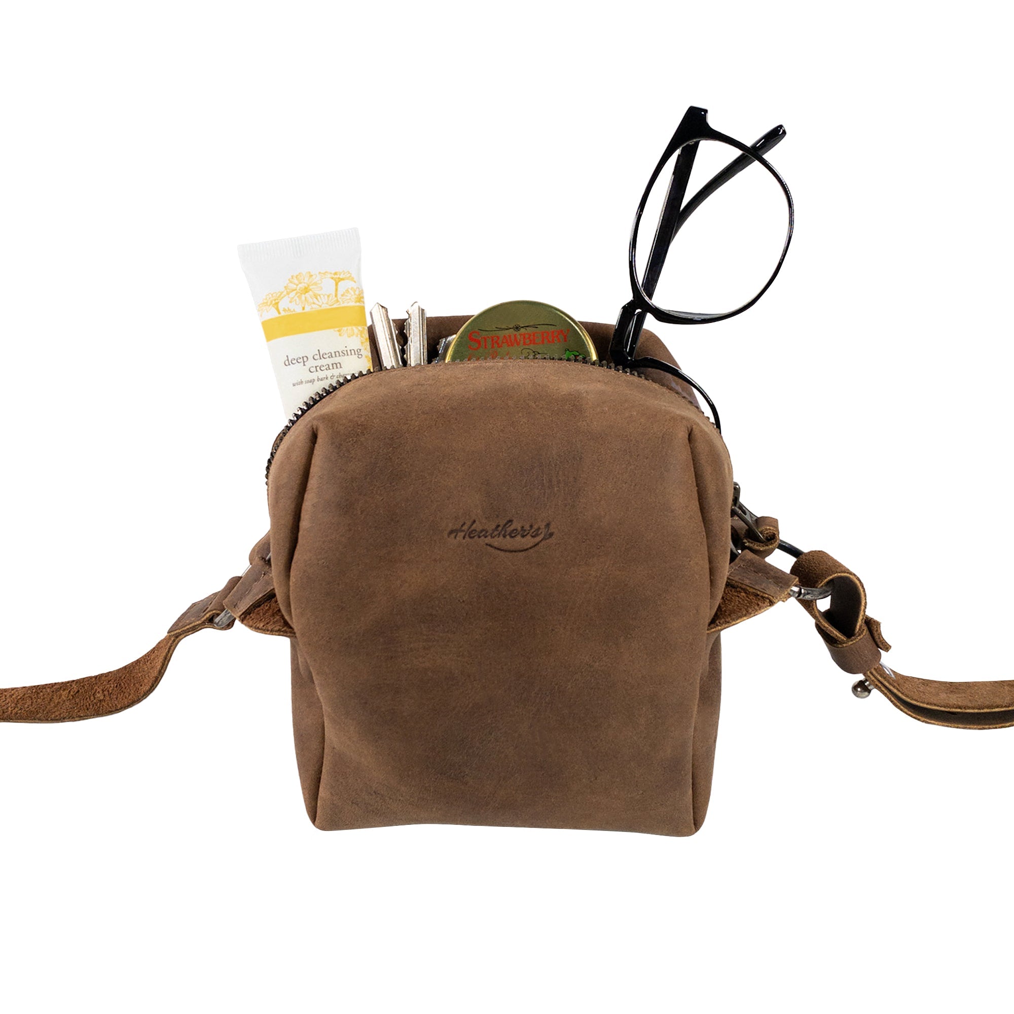 Heather's Cube Shaped Bag showcasing its rustic design filled with essential items. This Cube Shape Bag with Adjustable Shoulder Strap is a stylish Rustic Satchel, perfect as a Handbag or Purse made from premium Full Grain Leather. It reflects StockyardX's commitment to Small Batch Production, featuring Hand Cut and Hand Sewn craftsmanship, Fire Branded for authenticity, and is Handmade in La Antigua Guatemala & Oaxaca Mexico.