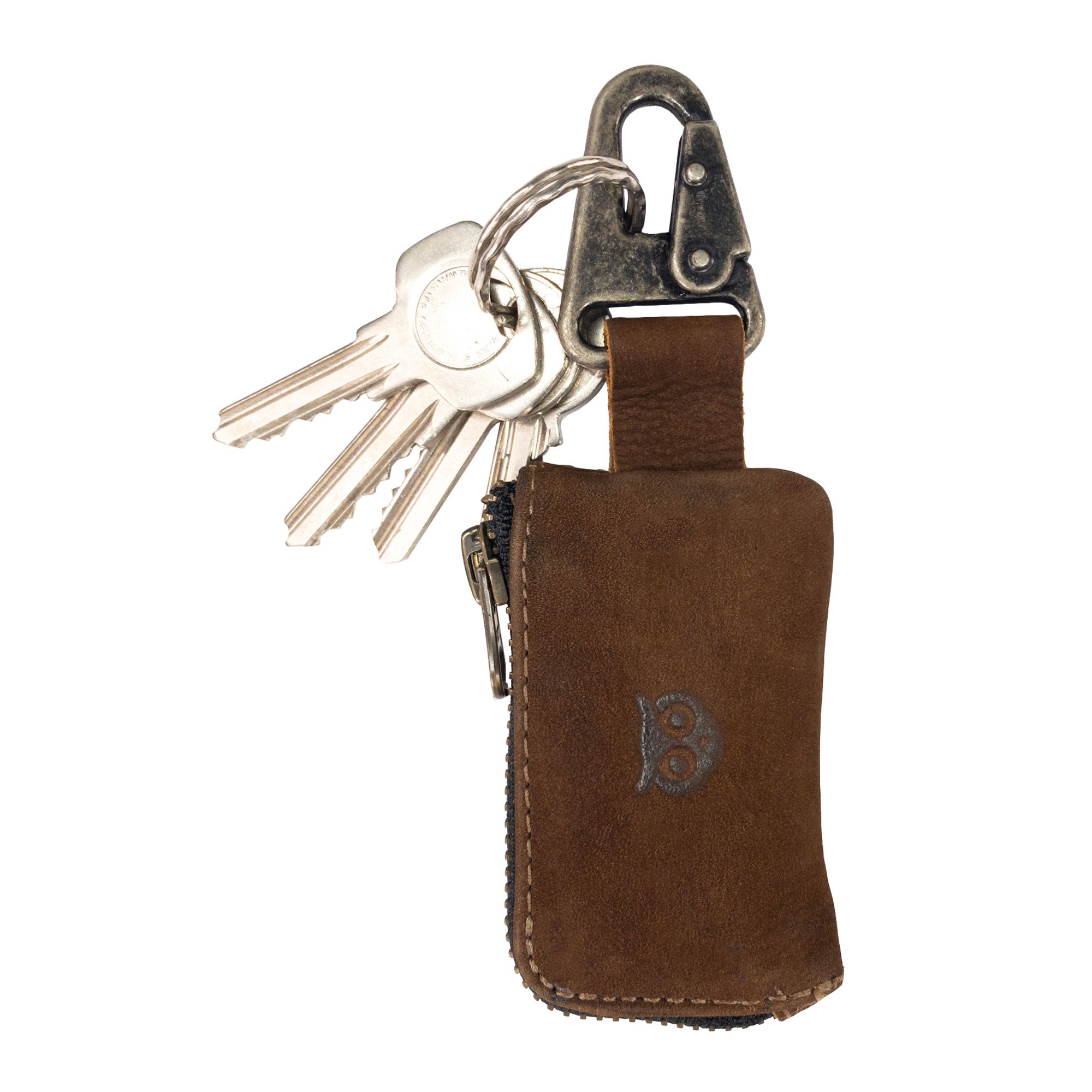 A close-up of Hide & Drink's Car Key Holder reveals its rustic leather key fob attached to keys, showcasing its secure zipper design. This Car Key Holder not only secures keys but also acts as a cash zipper case, ready for your headphone and charging cables, memory cards, and flash drives. Crafted with a nickel metal clasp and full grain leather, it embodies artisan craftsmanship with hand cut and hand sewn techniques, made in La Antigua Guatemala & Oaxaca Mexico.