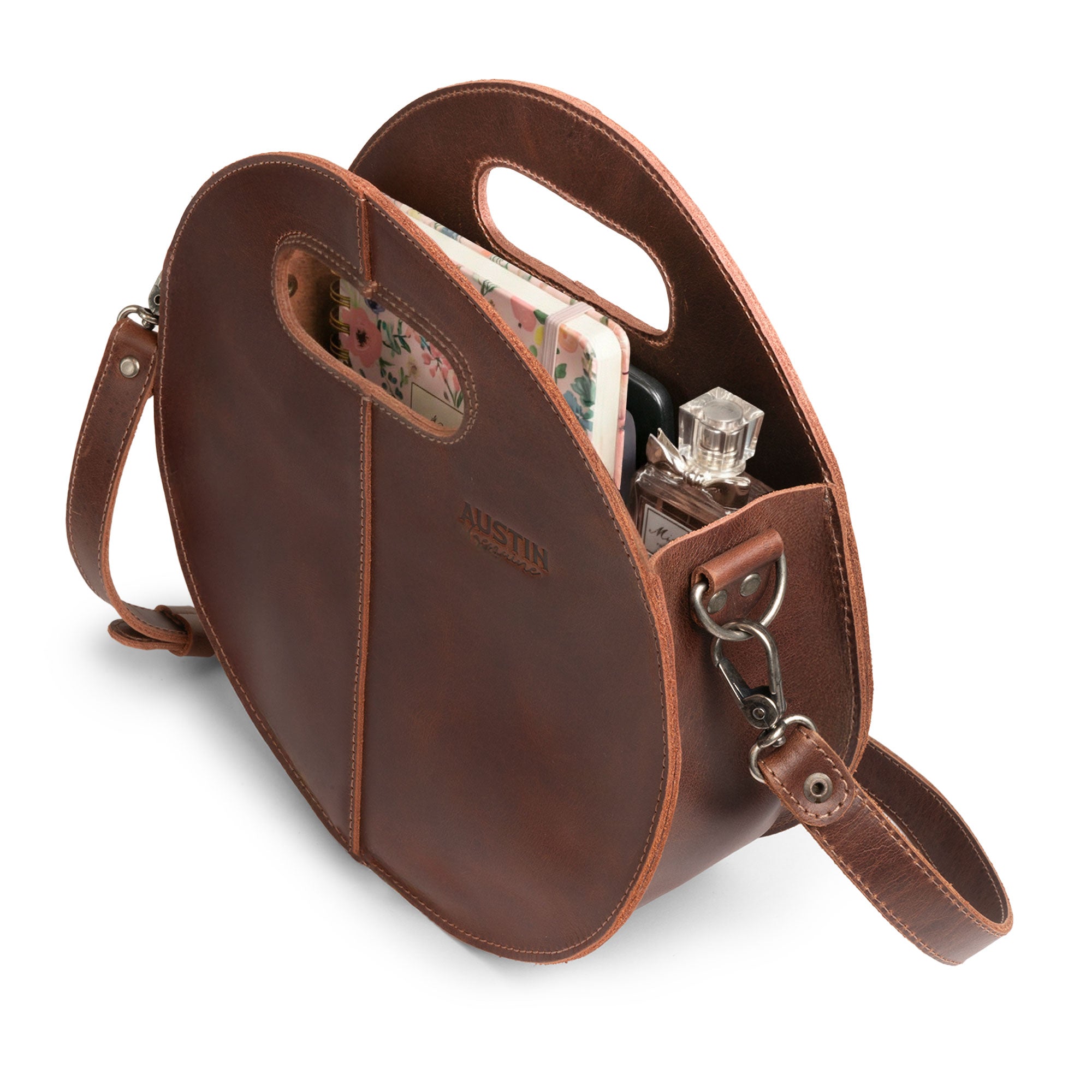 The Pecan Shoulder Bag by Austin Genuine, opened to reveal its organized interior, designed for functionality and style, crafted from full grain leather, representing small batch production and handmade techniques, hand cut and hand sewn by artisans in La Antigua Guatemala & Oaxaca Mexico.