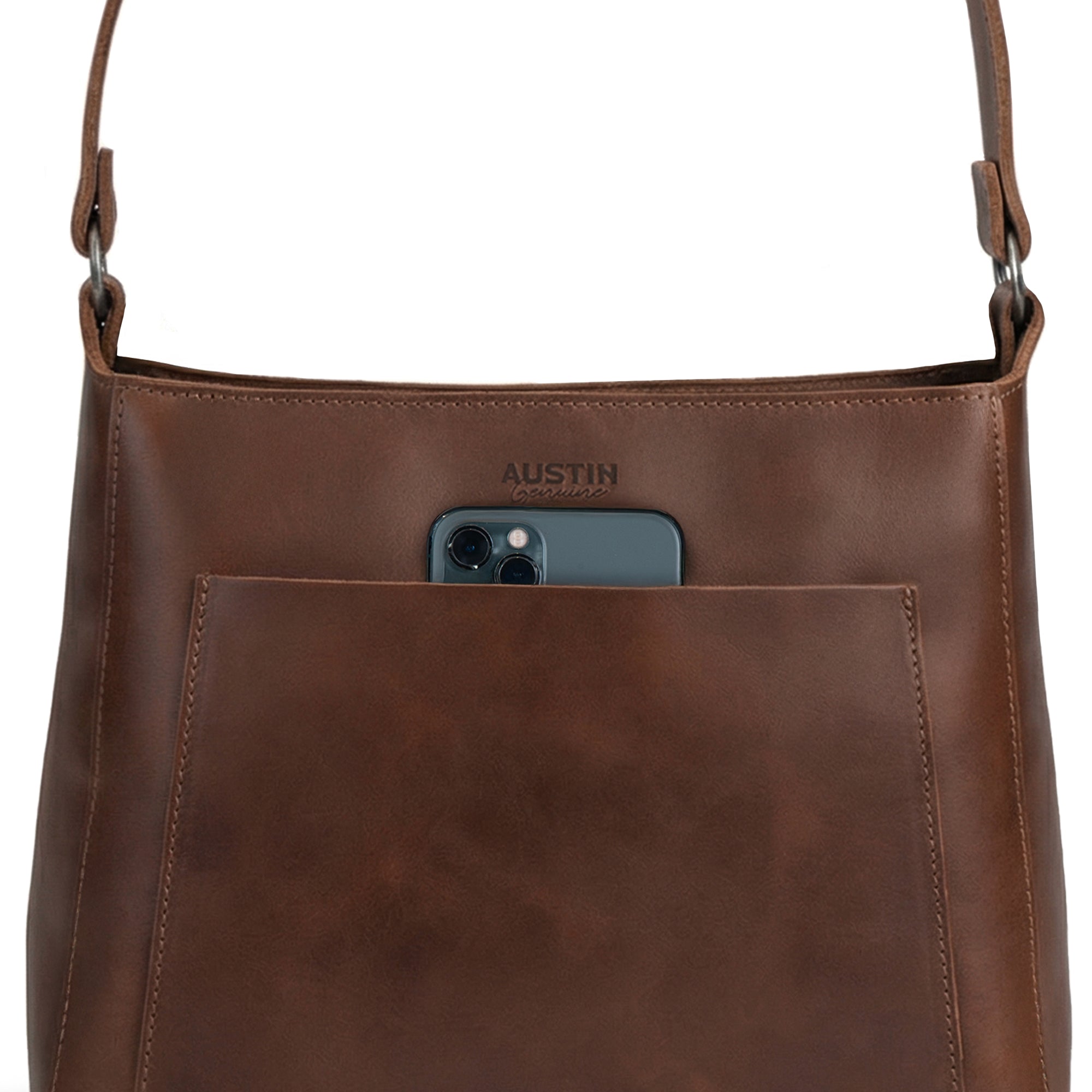 The Allandale Tote Bag by Austin Genuine, highlighting its exterior pocket holding a phone. Made of full grain leather, this artisan tote is a result of small batch production, hand cut and hand sewn techniques, and is fire branded, handmade in La Antigua Guatemala & Oaxaca Mexico.