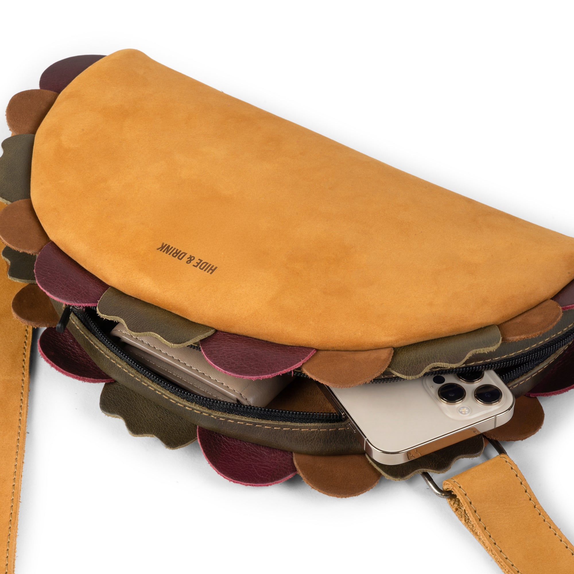 Close-up view of the Taco-Shaped Crossbody Bag by Hide & Drink, showcasing the clever zipper design and soft leather. The Leather Taco-Shaped Crossbody Bag with Adjustable Shoulder Strap is versatile for both men and women, doubling as a travel backpack or purse. Each piece is handmade in La Antigua Guatemala & Oaxaca Mexico, ensuring unique quality.