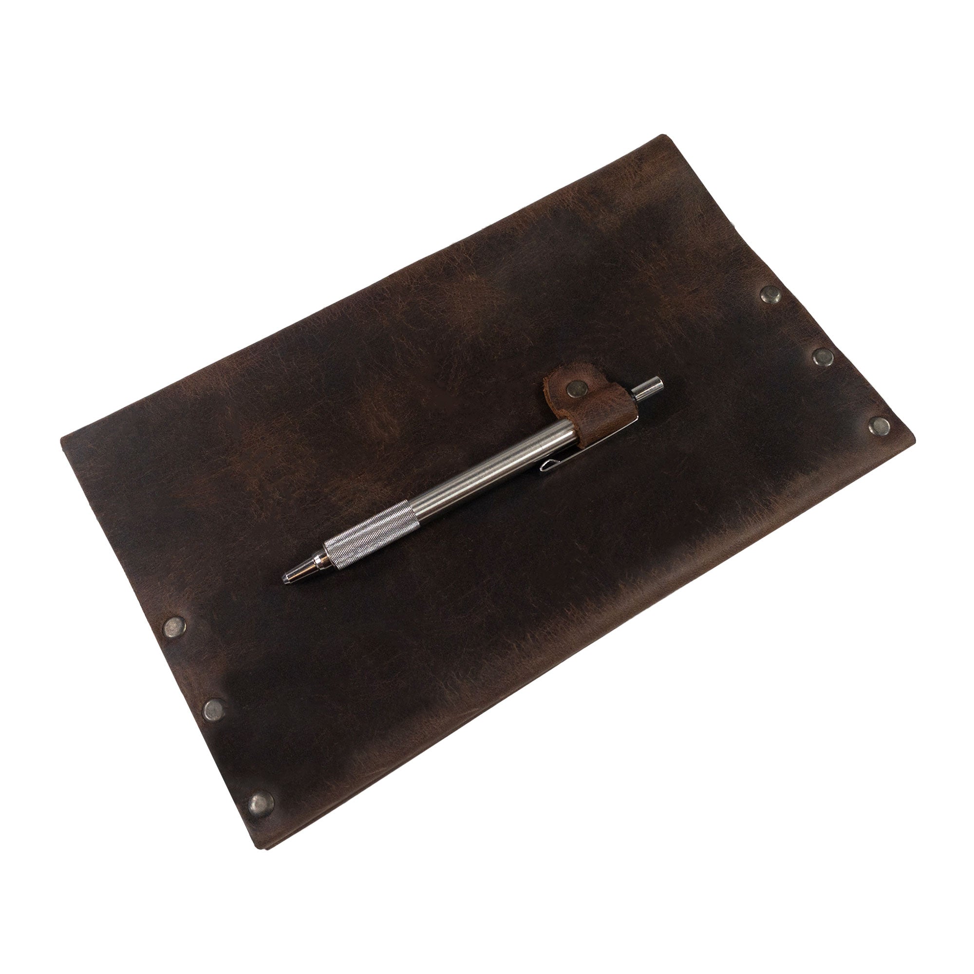 A stylish pen rests on Hide & Drink's Riveted Journal Cover (5 x 8.50 in.) (Notebook Not Included), which exemplifies a classic sleeve design crafted from vintage style full grain leather. This artisan product emphasizes small batch production with hand cut and hand sewn techniques, fire branded for an authentic touch, made by skilled artisans in La Antigua Guatemala & Oaxaca Mexico.