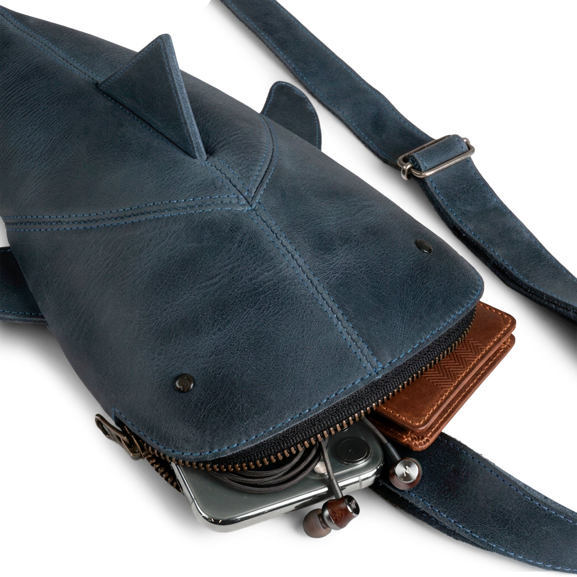 An overhead view of the Leather Shark Crossbody Bag by Hide & Drink, with its zippered compartment showcasing ample storage for essentials. This Leather Shark-Shaped Sling Bag, crafted from full grain leather, is perfect as a crossbody purse or messenger bag. Handcrafted in La Antigua Guatemala & Oaxaca Mexico, this bag exemplifies quality small batch production and artisan skills, making it an ideal choice for everyday use.