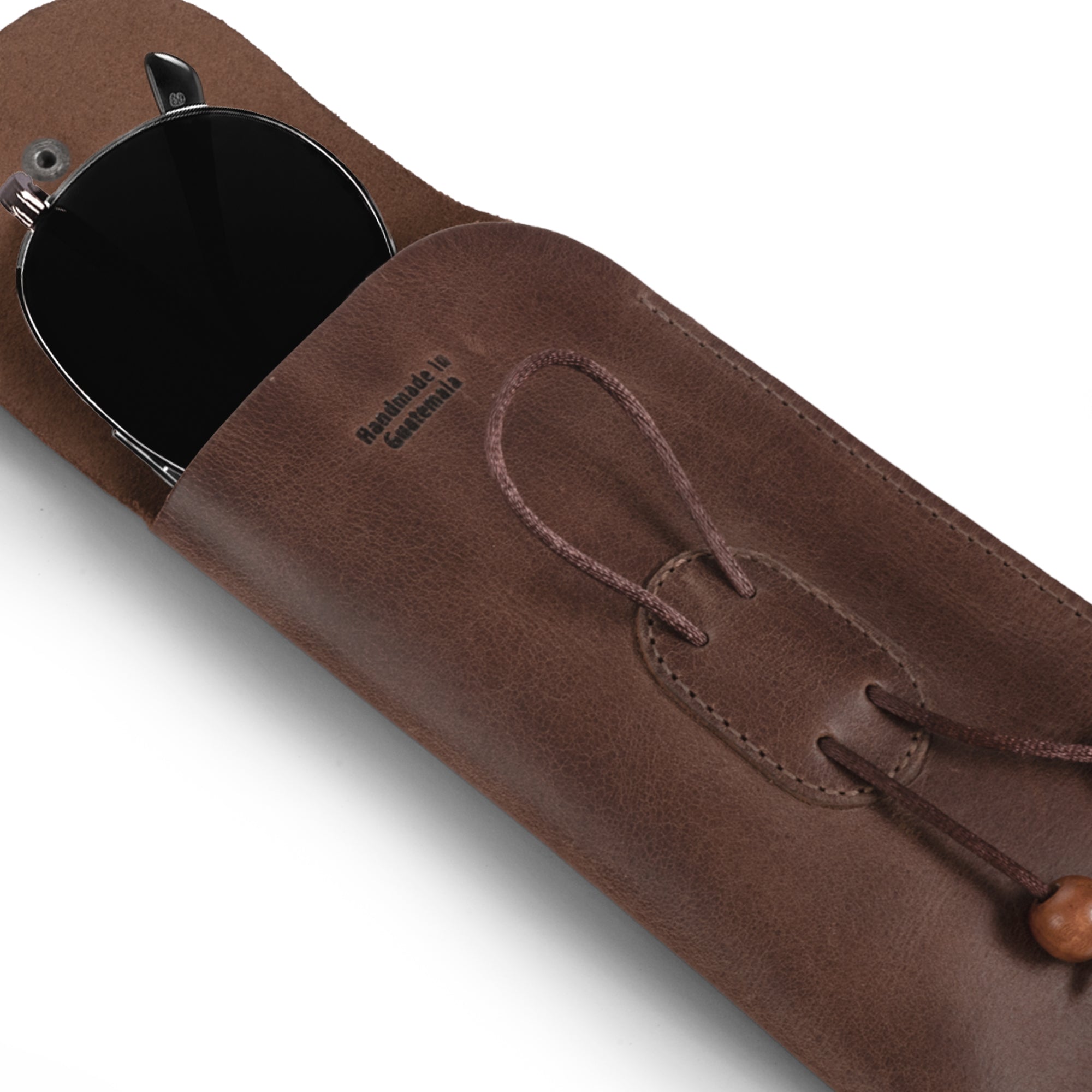 An open Slim Eyeglasses Case by Hide & Drink, displaying its inner details and functionality. This minimalist eyewear cover is crafted from full grain leather, designed for easy access to sunglasses or eyeglasses. It represents artisanal quality with hand cut and hand sewn features, perfect as a glasses pouch for travel and handmade in La Antigua Guatemala & Oaxaca Mexico.