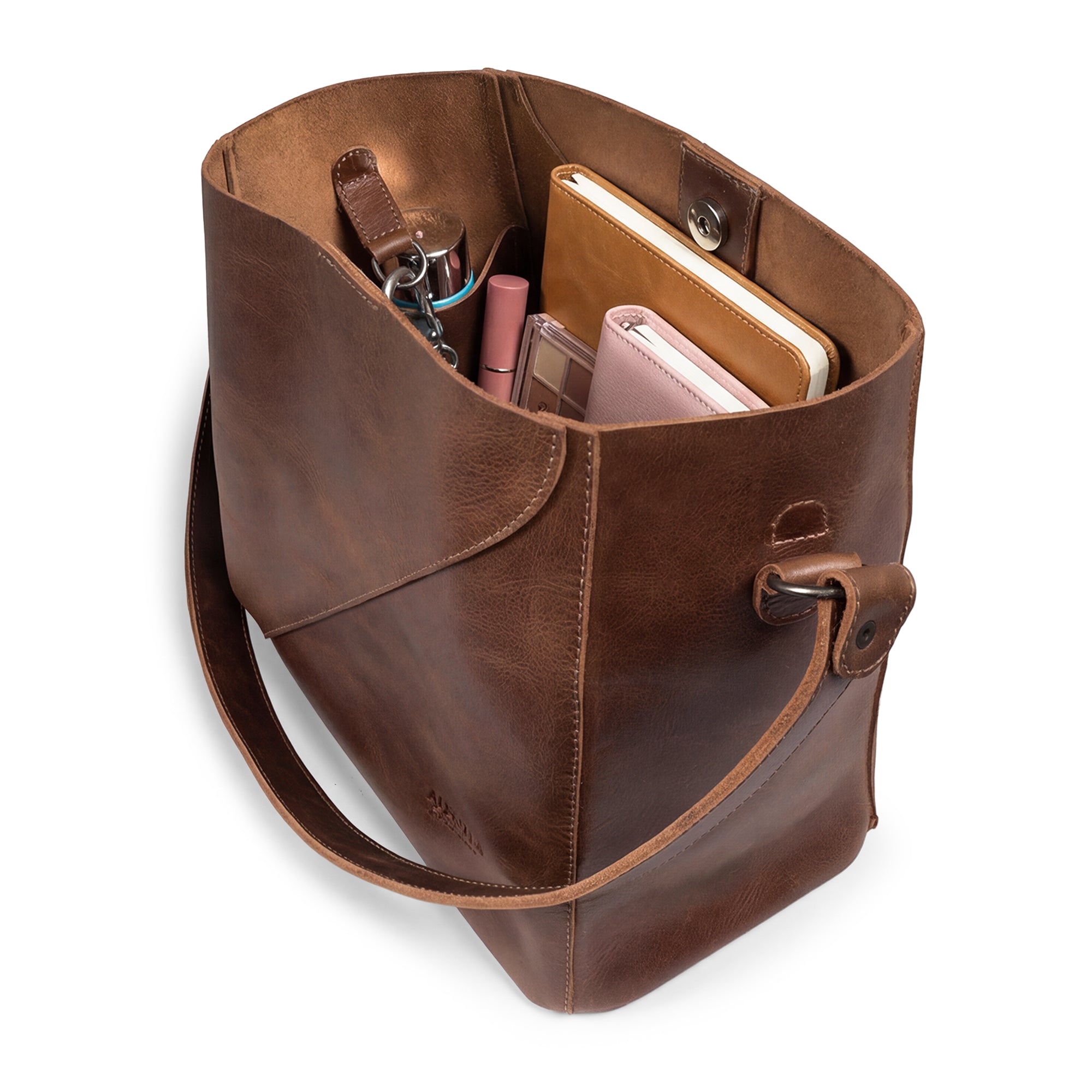 Top-down view of The Pemberton Shoulder Bag by Austin Genuine filled with essentials, highlighting its practical functionality and artisan quality, crafted from full grain leather.