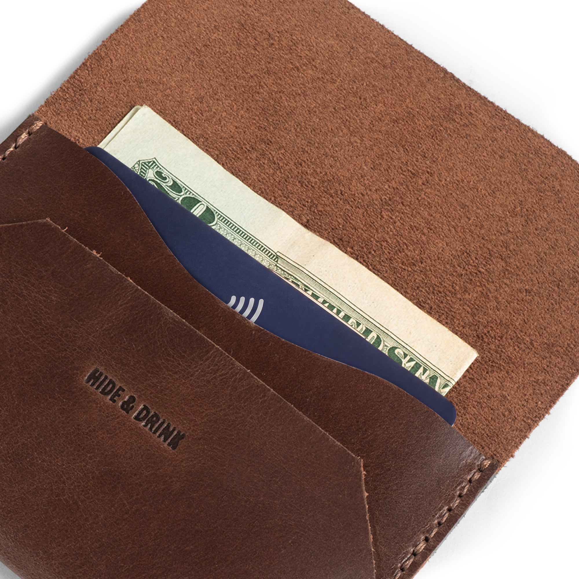 An open view of the Enfold Card Wallet by Hide & Drink displaying its functional interior with cash storage and card slots. This leather card wallet's slim design is perfect for front pocket convenience, serving as a compact credit card holder for men and a minimalist thin business card organizer. Made from full grain leather, it features small batch production, hand cut and hand sewn craftsmanship, with fire branding that highlights artisan skills from La Antigua Guatemala and Oaxaca Mexico.