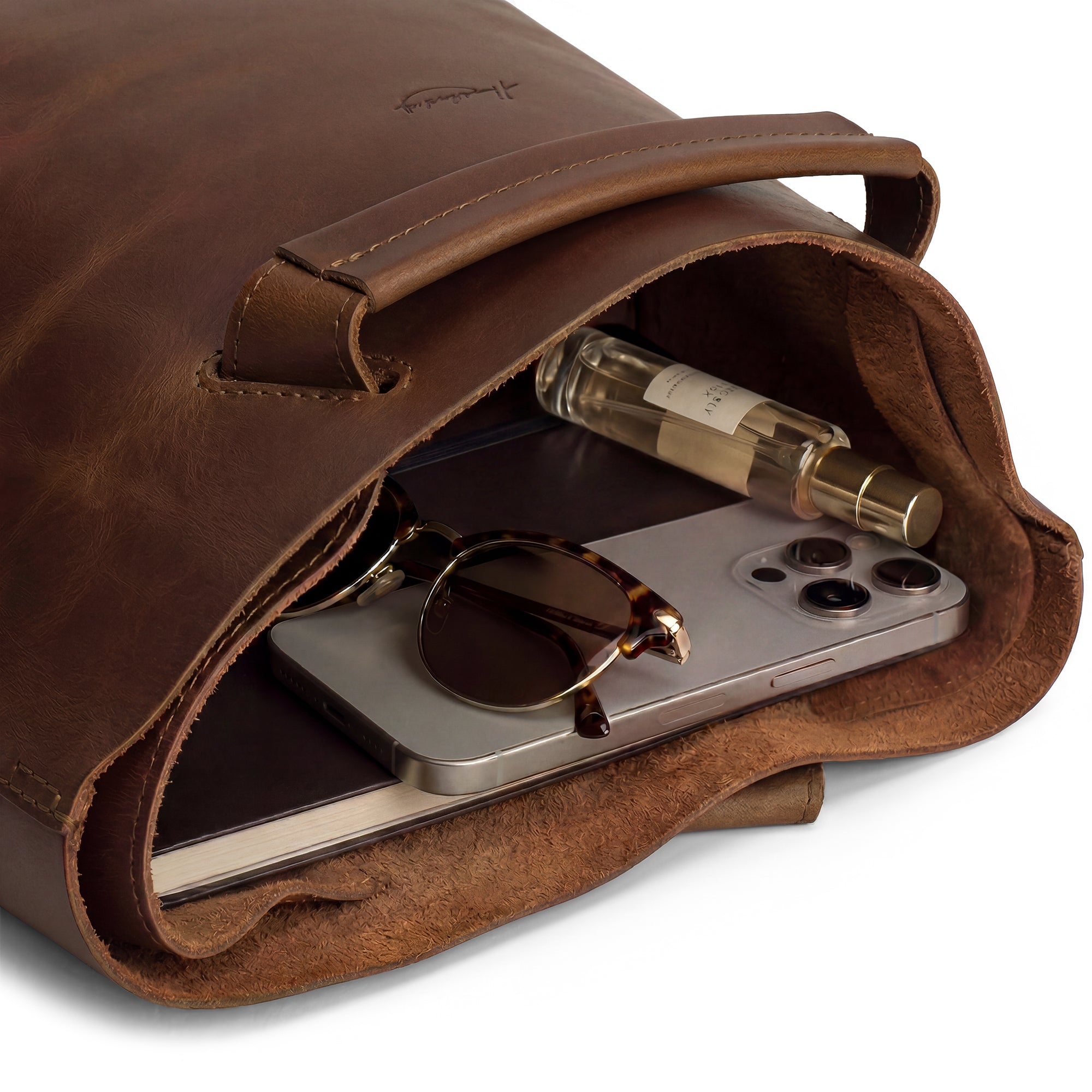 Inside view of Heather's Convertible Backpack to Shoulder Bag, showing essential items like a phone and sunglasses nestled within. This Spacious Crossbody for Women combines functionality and style, featuring a Squared Purse design made from high-quality Full Grain Leather through Small Batch Production with a focus on artisan craftsmanship, handmade in La Antigua Guatemala & Oaxaca Mexico.