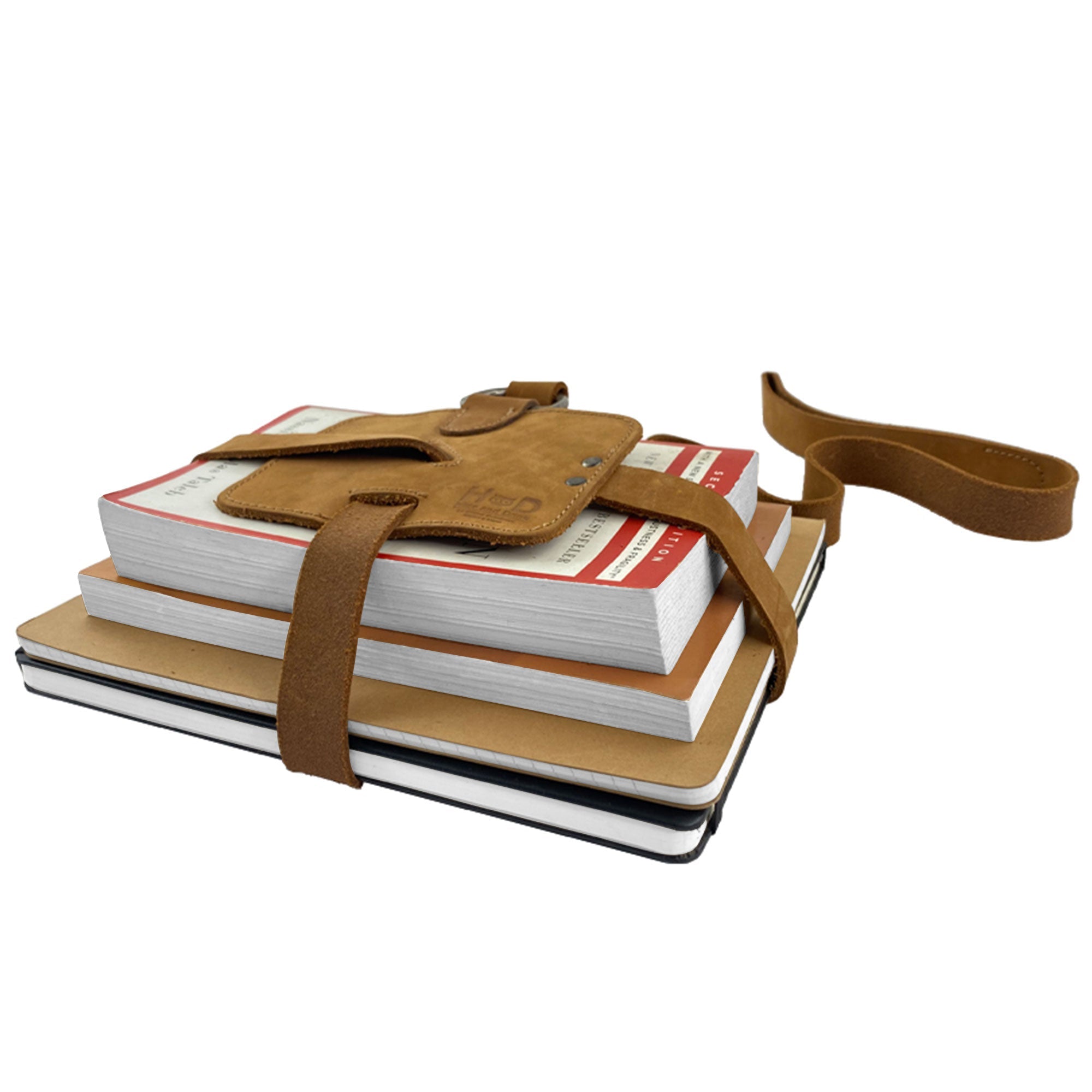 The Hide & Drink Book Strap Carrier used with a stack of notebooks, demonstrating its secure holding ability. This Full Grain Leather accessory, handmade in La Antigua Guatemala, is perfect for on-the-go readers.