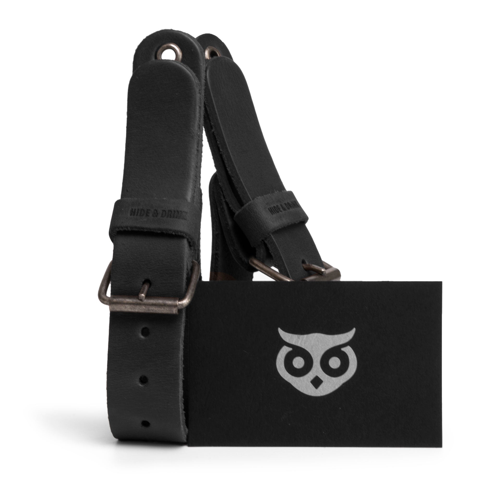 Image of a black Hide & Drink Wall Hanging Strap with a branding tag, showcasing the quality and craftsmanship of this leather product. Perfect for organizing axes, hatchets & tools, this heavy-duty tool hanger is made from full grain leather. Its design highlights small batch production, with each item being artisan hand cut and hand sewn in La Antigua Guatemala & Oaxaca Mexico.