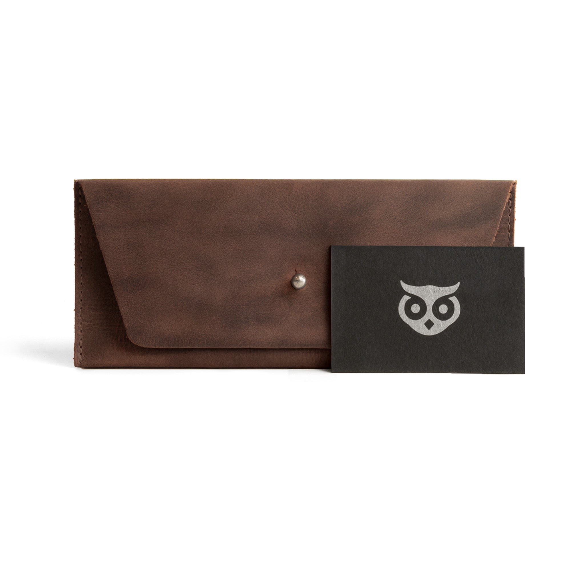 Stylish presentation of the Long Utility Pouch by Hide & Drink alongside a card, emphasizing its unique design and artisan craftsmanship. Ideal for carrying cash, coins, and cards, made from full grain leather.