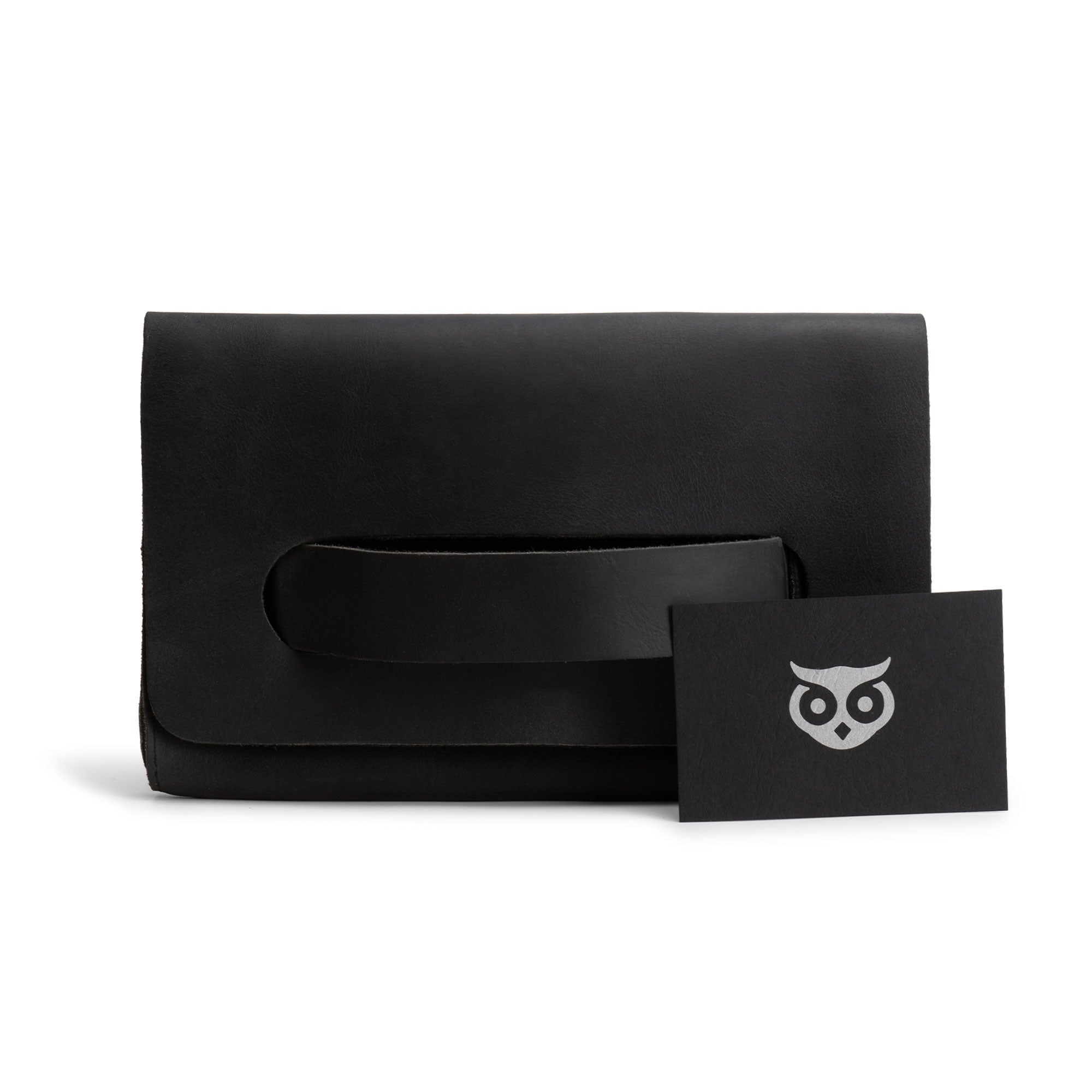 The black Clutch Bag With Handle by Hide & Drink displayed with a business card. This Full Grain Leather Clutch Bag is a chic option for women as a handbag or night bag, showcasing small batch artisan production from Guatemala and Mexico.