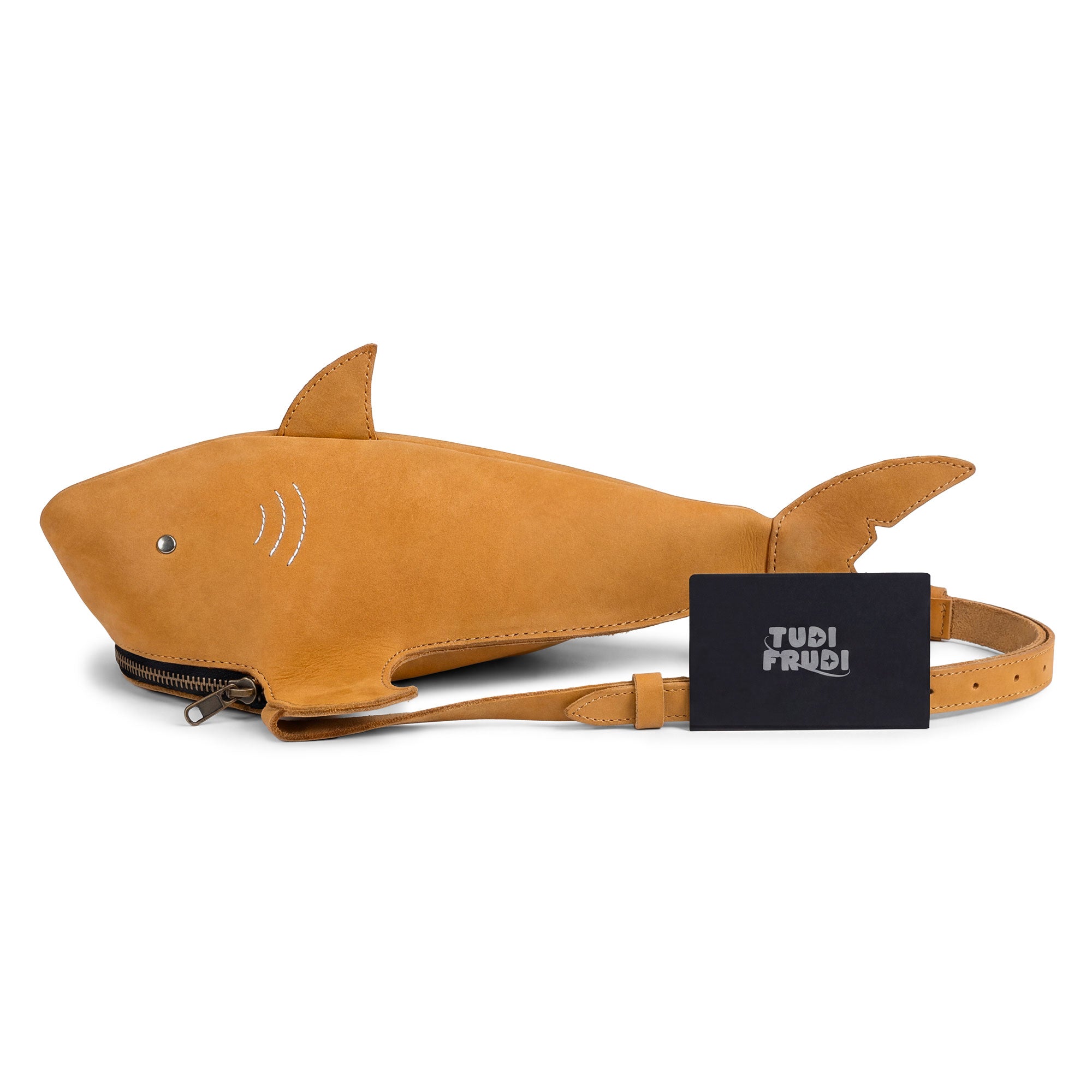 The Shark-Shaped Shoulder Bag by Tudi Frudi displayed alongside its branding card. This eye-catching accessory, made from premium Full Grain Leather, is a testament to artisan craftsmanship with its hand sewn details, adjustable strap, and versatile use as a crossbody or messenger bag.