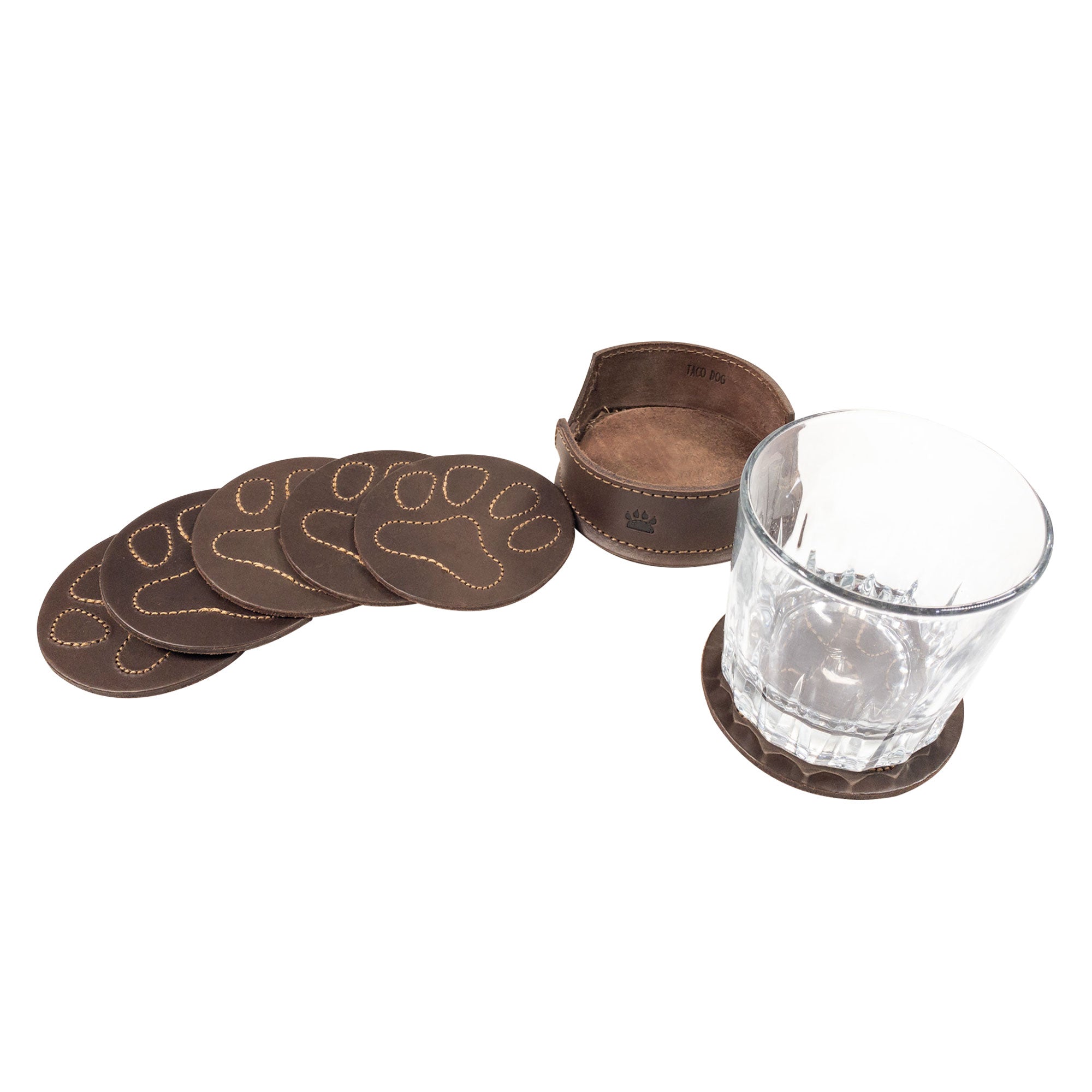 Elegant display of Taco Dog Paw Print Coasters arranged with a glass, showcasing their durable design. This set of 6 with holder is ideal for home decor, effectively protects your table from hot & cold drinks, and makes a thoughtful gift for dog lovers. Crafted from full grain leather in small batch production in La Antigua Guatemala.