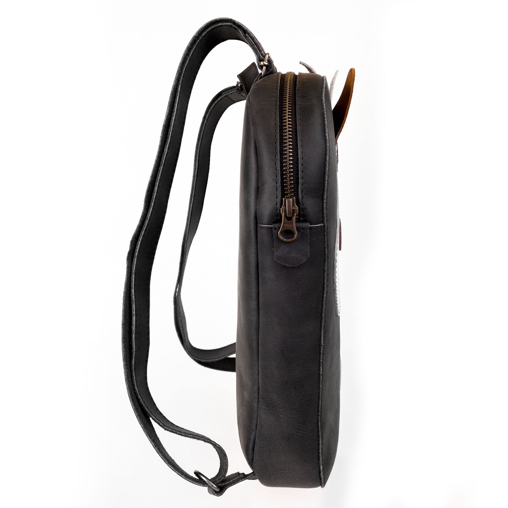 Another side view of the Hide & Play Daily Backpack with Unicorn Design, focusing on its slim design and practical zipper. Made from premium full grain leather, this casual bag is suitable as a messenger bag or travel bag for men and women. Each backpack is artisan handcrafted in La Antigua Guatemala, representing small batch production and quality craftsmanship.
