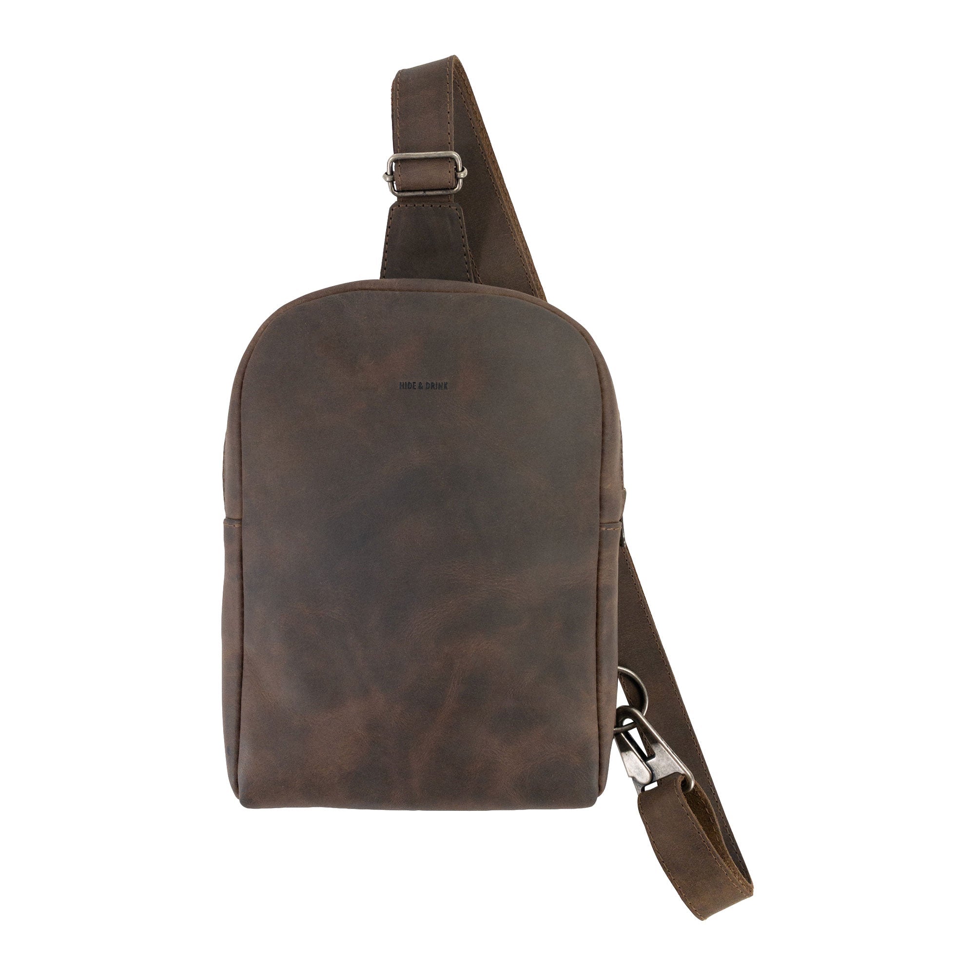 Showcasing the Hide & Drink Crossbody Rounded Bag with tags and details. This Rounded Crossbody Bag with Adjustable Strap stands out as a travel accessory made from Full Grain Leather, highlighting the craftsmanship of small batch artisan production from La Antigua Guatemala & Oaxaca Mexico.