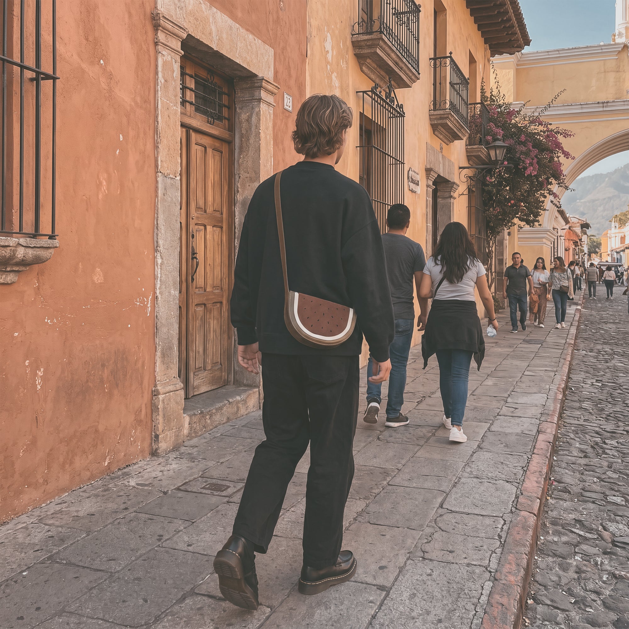 Woman wearing a Watermelon-Shaped Shoulder Bag by Tudi Frudi showcasing its stylish design and adjustable strap. This trendy Crossbody Bag and Messenger Bag is made from premium Full Grain Leather, emphasizing small batch production, hand cut, hand sewn, and fire branded artistry. Handmade in La Antigua Guatemala & Oaxaca Mexico.