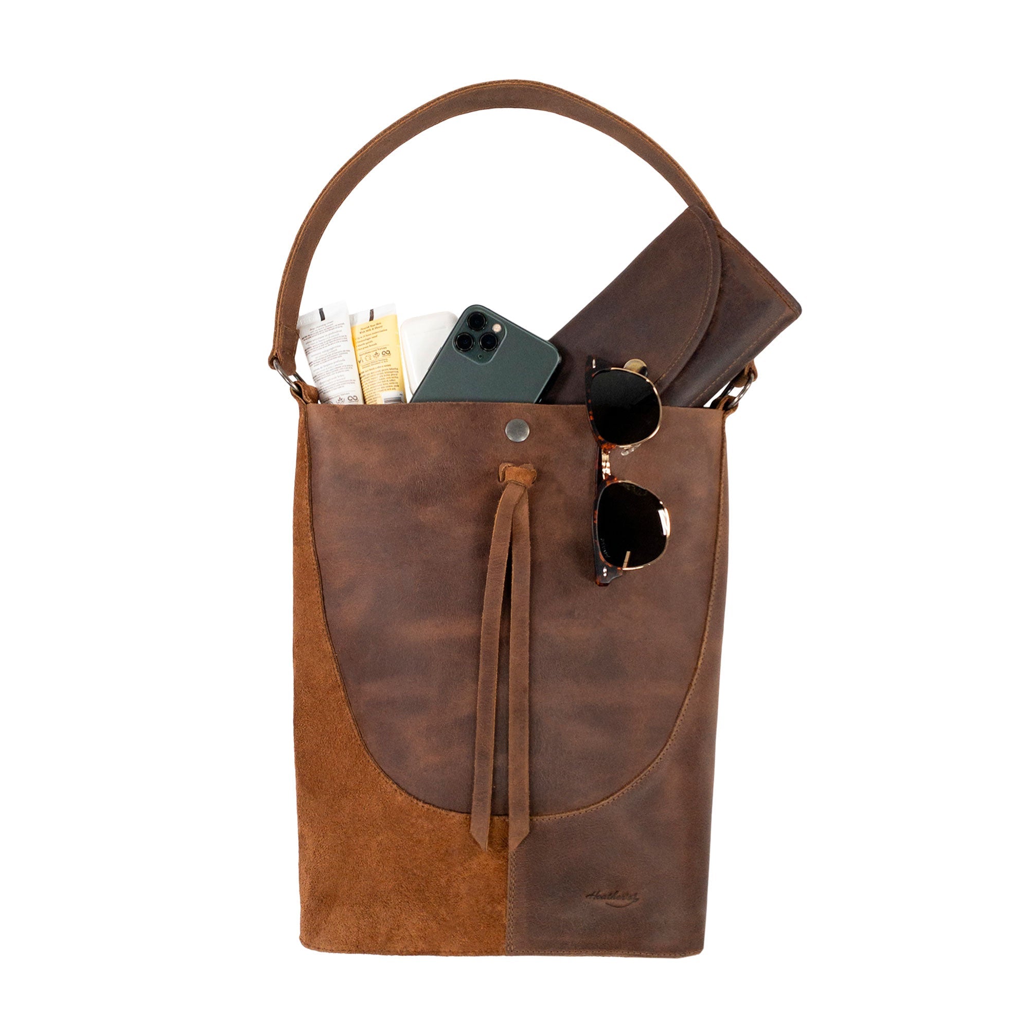 Heather's Reversed Shoulder Bag filled with personal items, demonstrating its practicality as a travel bag. This rustic tote bag for women combines a vintage purse style with a shoulder bag strap, made from high-quality full grain leather, hand cut and sewn in La Antigua Guatemala & Oaxaca Mexico.