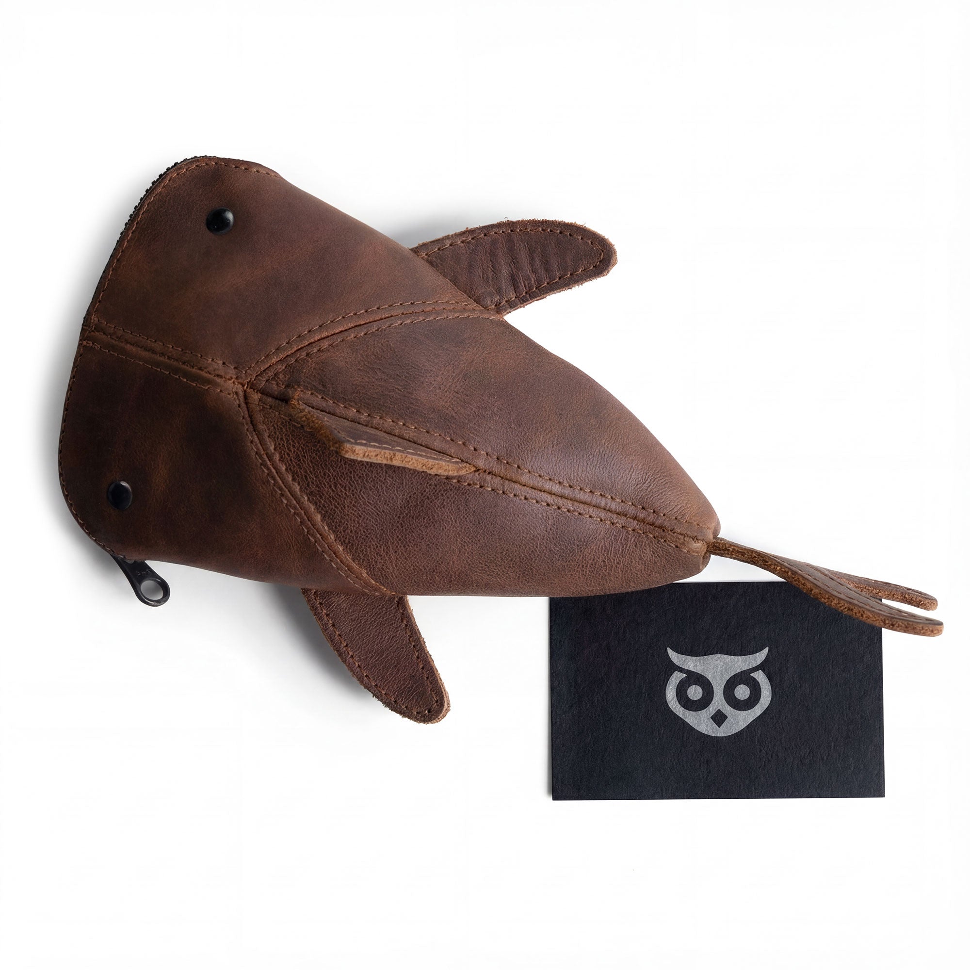 The Leather Shark Pouch by Hide & Drink alongside a brand card, showcasing its charming design ideal for makeup, stuffed animal storage, and as a wallet, made from full grain leather, reflecting the craftsmanship of small batch production in La Antigua Guatemala & Oaxaca Mexico.