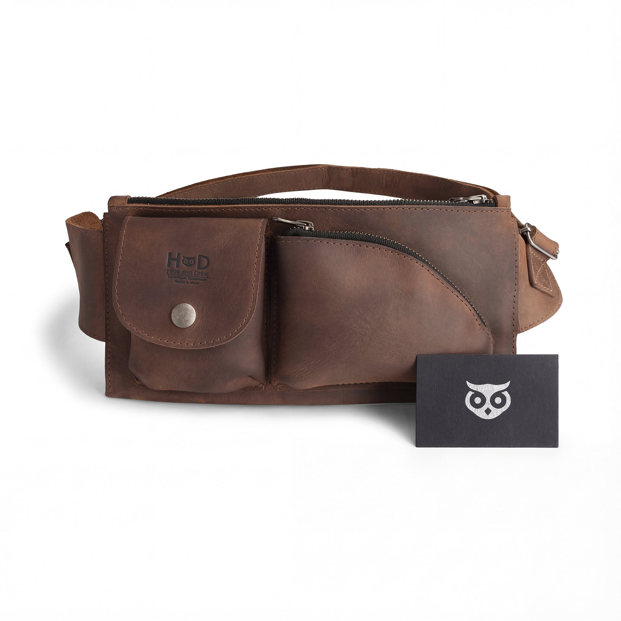 The Crossbody Multi-Pocket Bag by Hide & Drink is showcased with a care tag, emphasizing its authentic craftsmanship in full grain leather. Serving as a stylish Crossbody Bag, Messenger Bag, or Shoulder Bag, it is also a great Travel Accessory. This handmade item is a proud result of small batch production techniques from La Antigua Guatemala & Oaxaca Mexico.